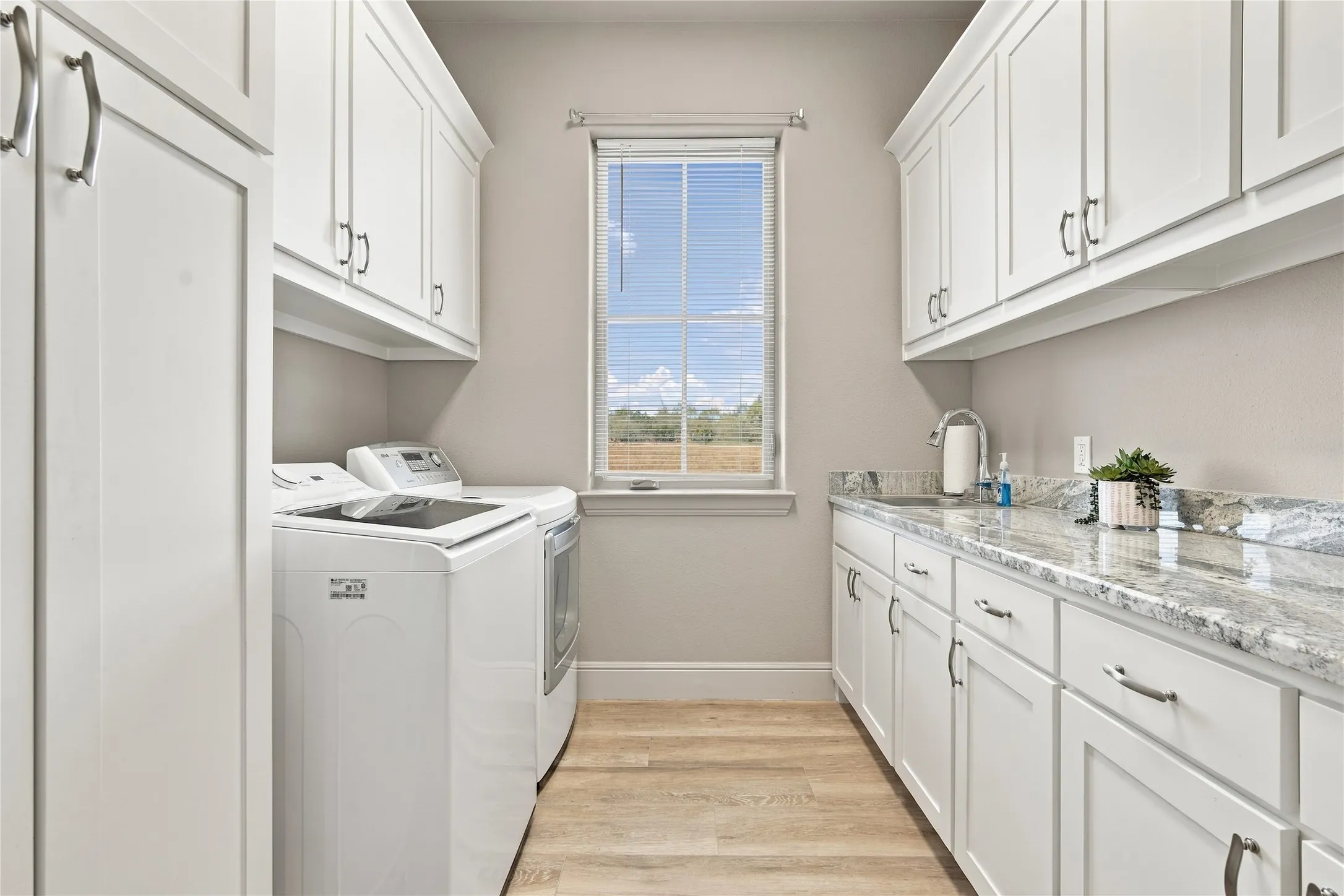 Built-in cabinetry and a stone countertop with integrated sink make laundry day a breeze.