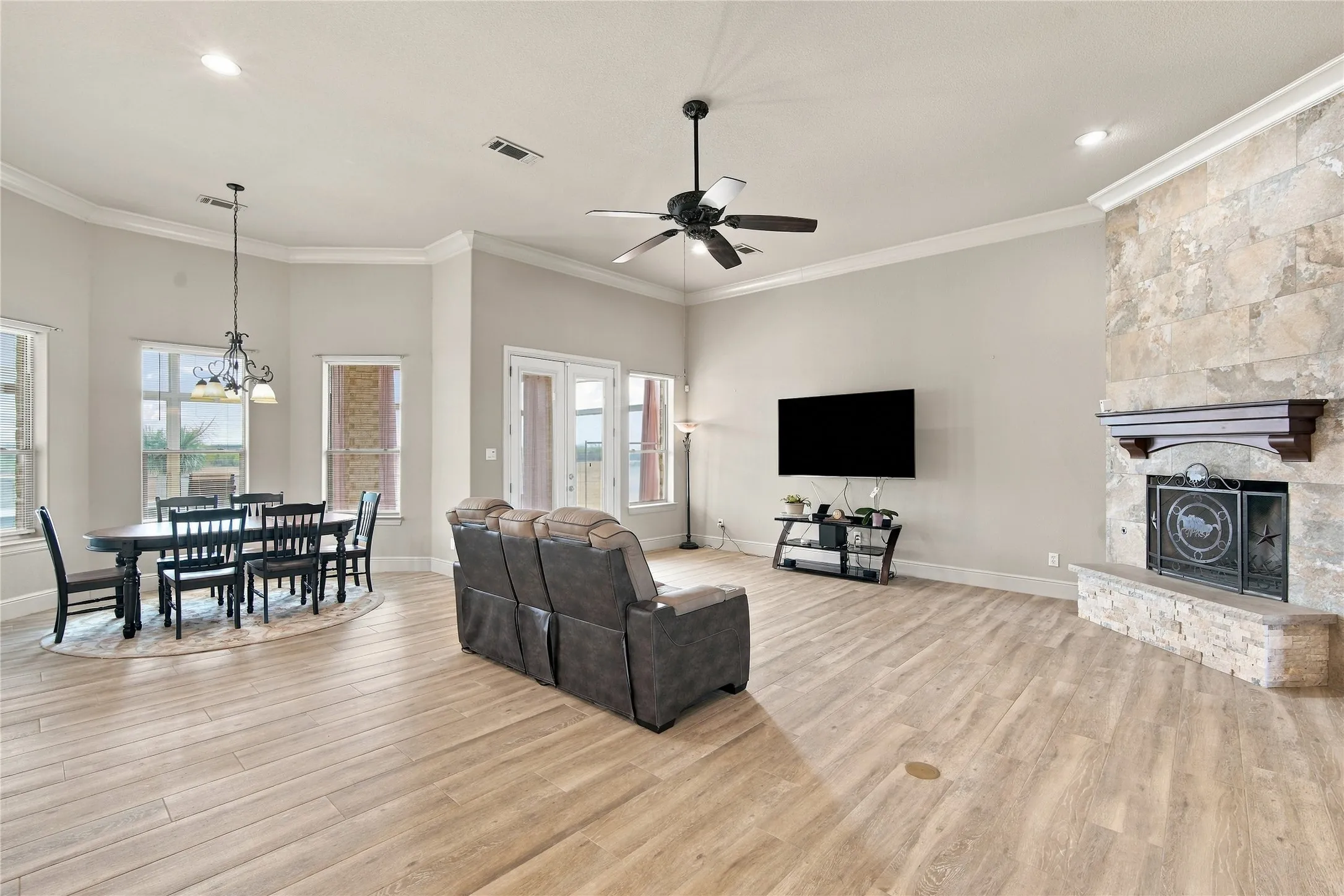 Gather around the stone fireplace in this bright living area, where tile flooring and oversized windows make entertaining easy.