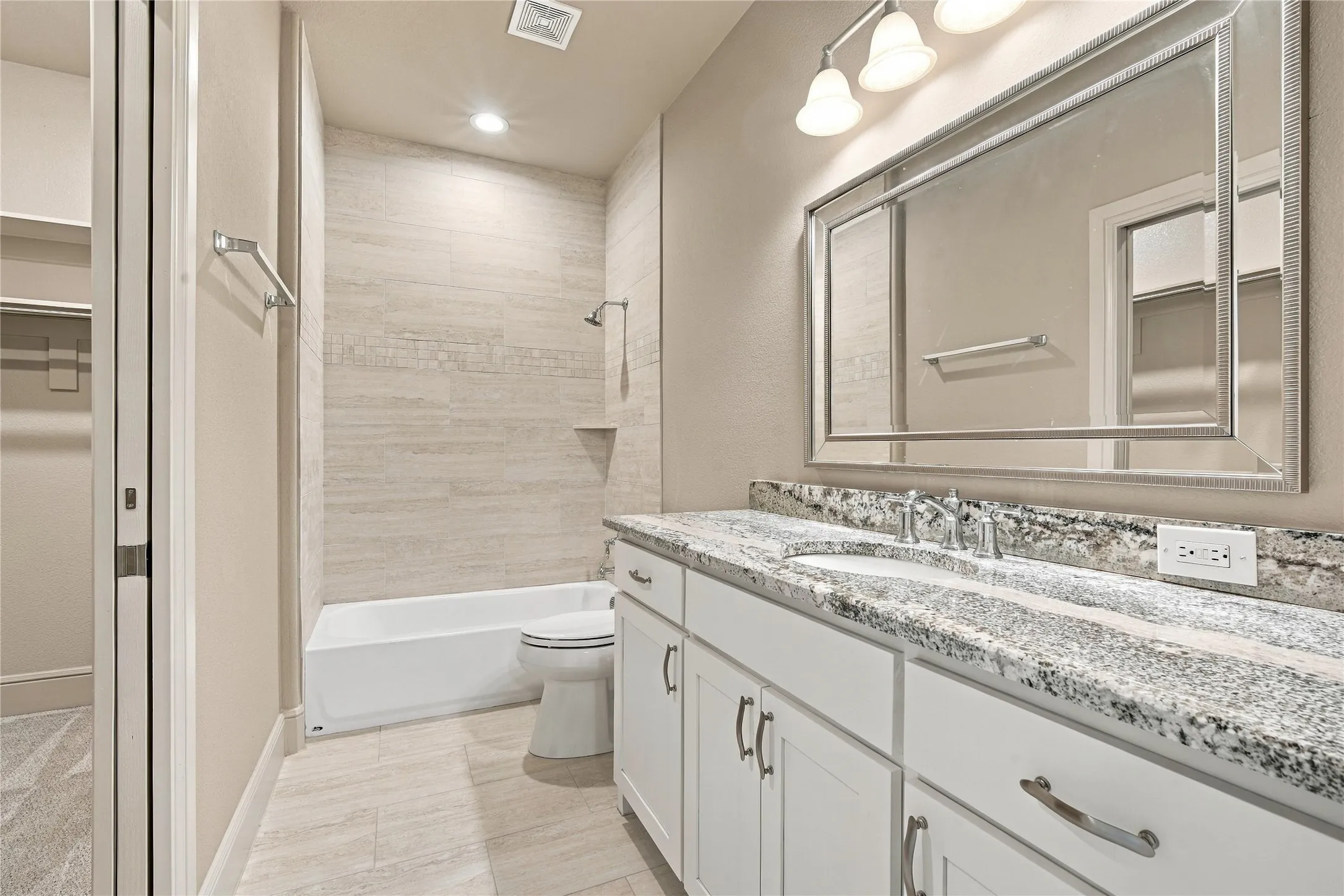 A well-appointed secondary bath with granite counters and clean white cabinetry.