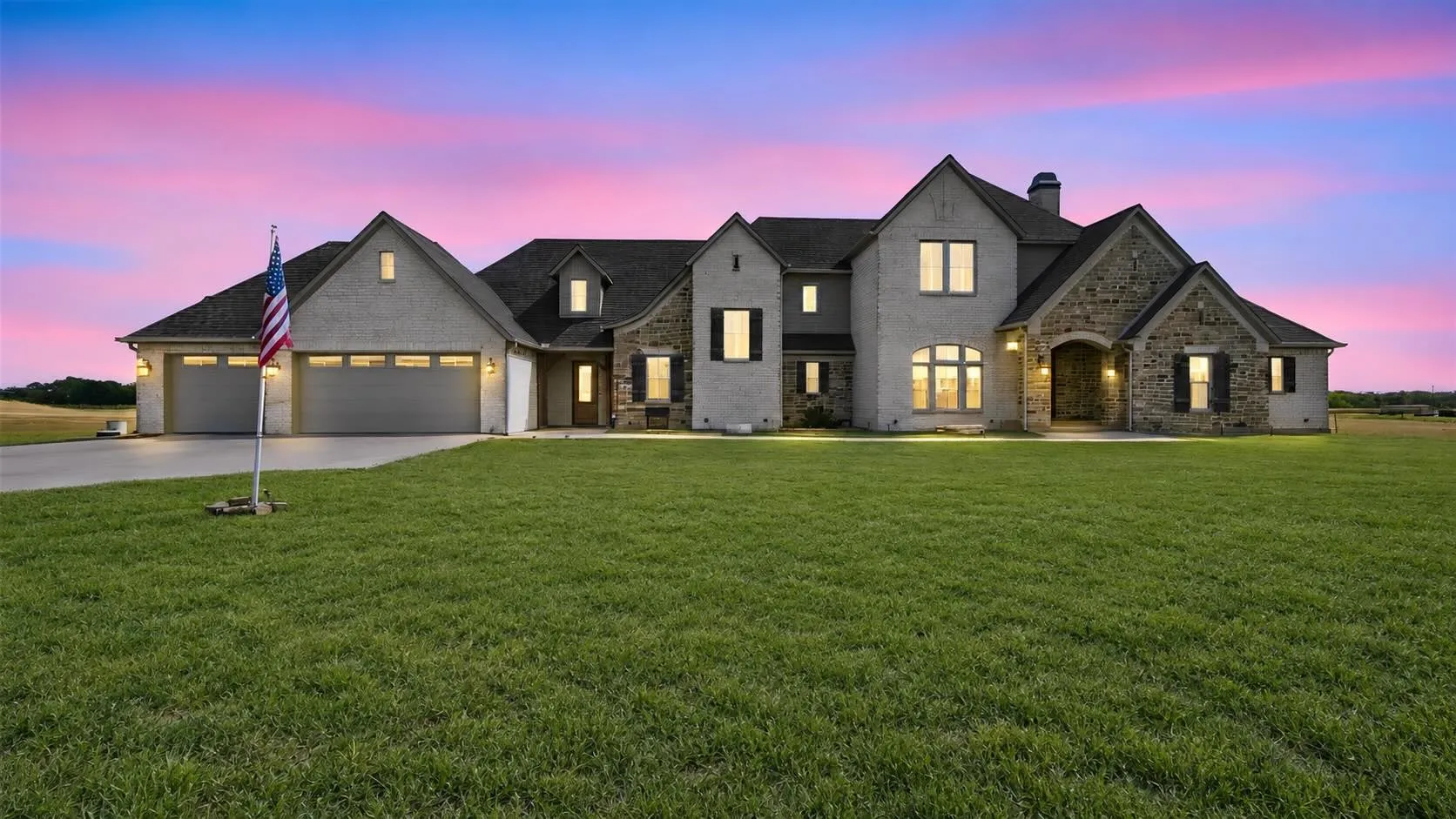 Stunning stone-and-brick facade with a dramatic arched entry and three-car garage, setting the tone for the whole home.