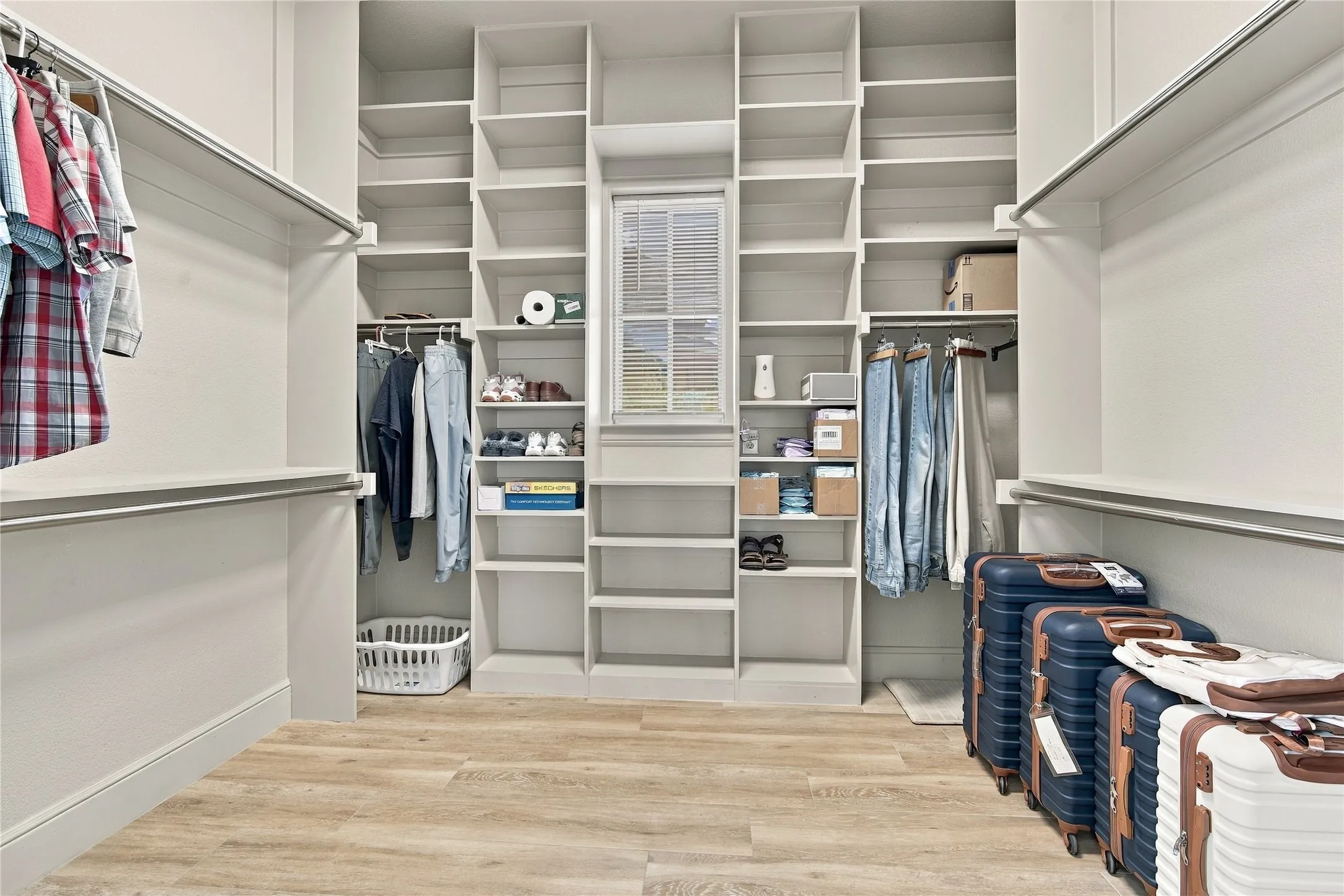 Custom built-in shelving and hanging rods keep the primary closet organized, with natural light streaming in.
