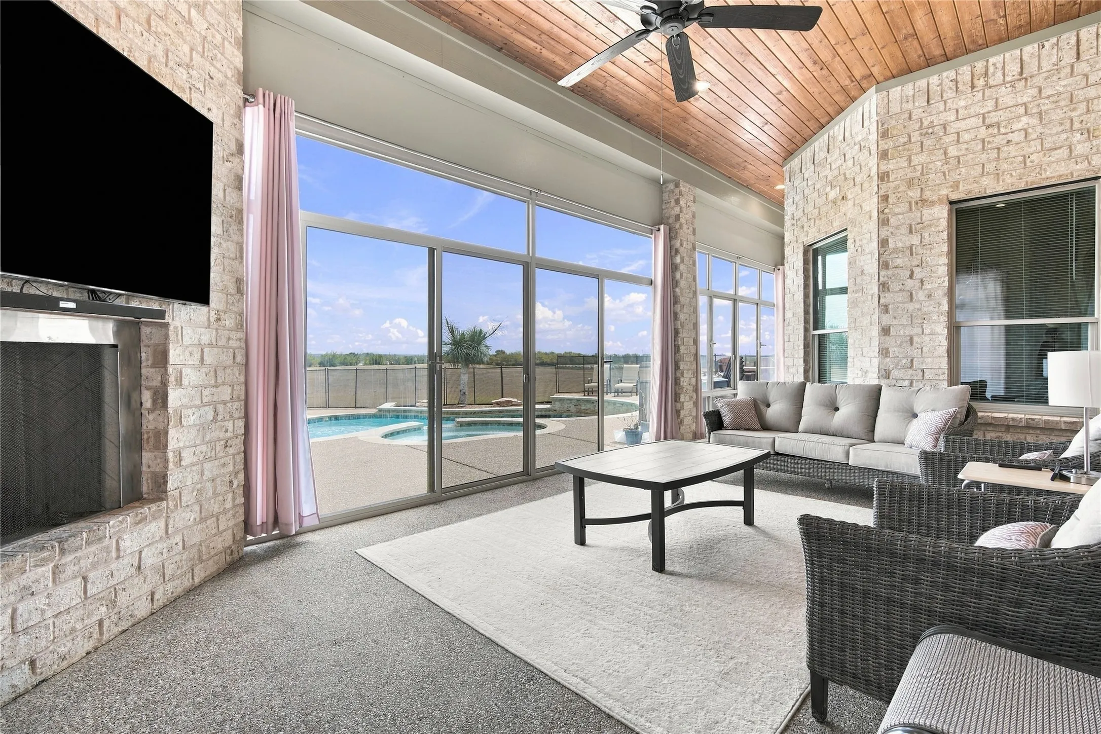 Relax under the vaulted, wood-paneled covered patio, complete with a stone fireplace, ceiling fan, and sliding glass doors that open straight into the living room.