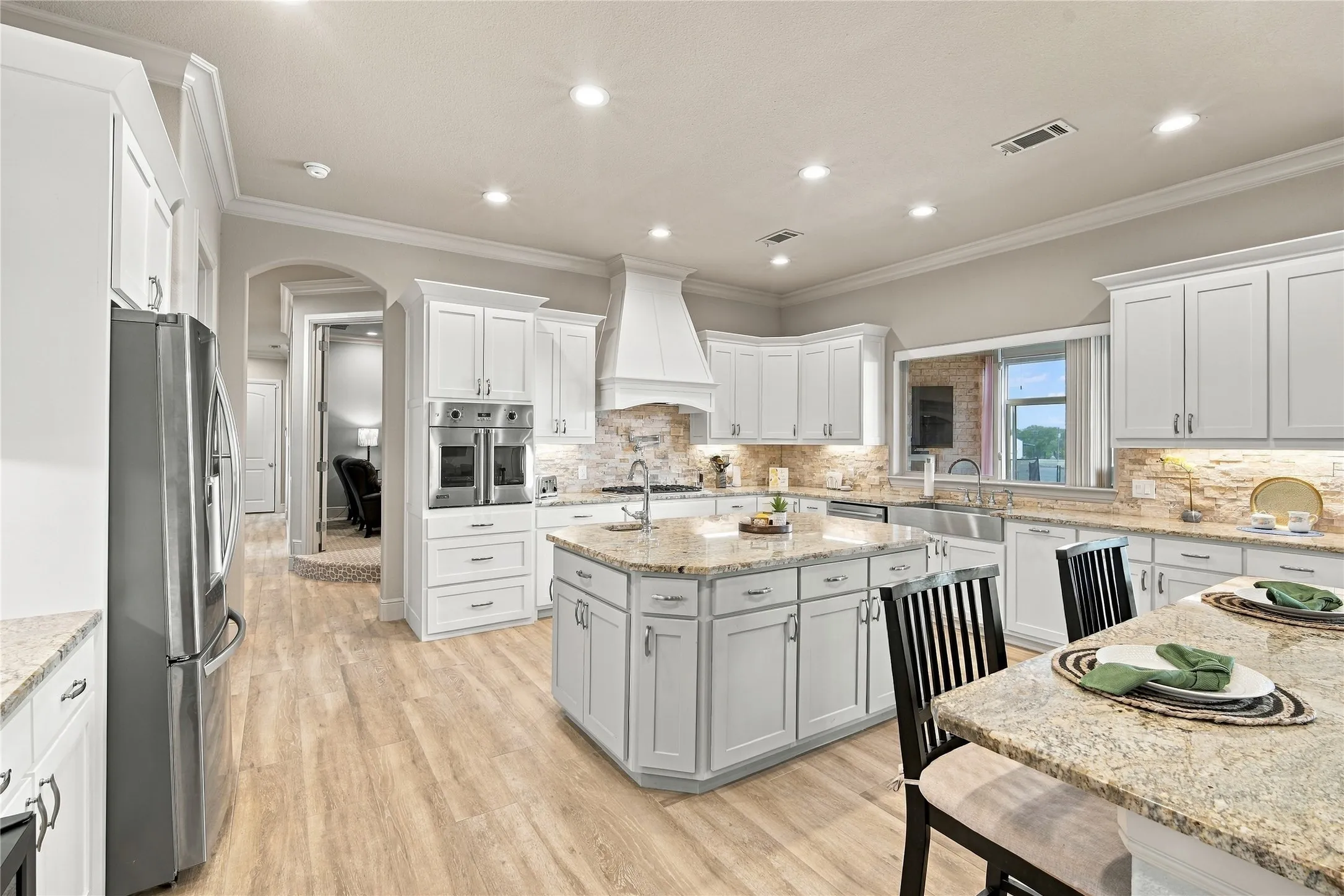 Whip up weeknight dinners or holiday feasts in this open kitchen, featuring white cabinetry, granite counters, and tile flooring.