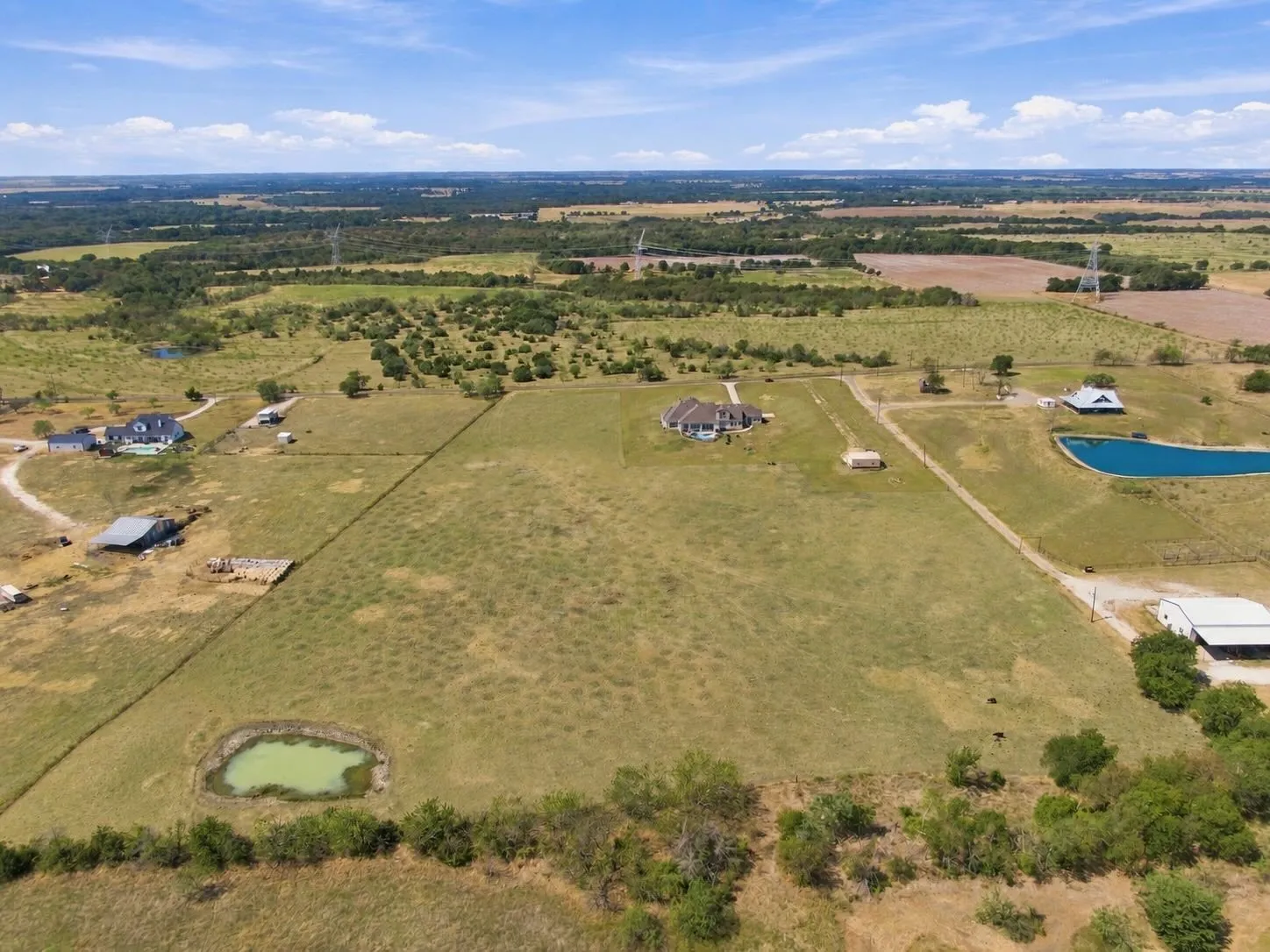 From above, take in the scale of this expansive property, complete with two ponds and multiple outbuildings for endless possibilities.