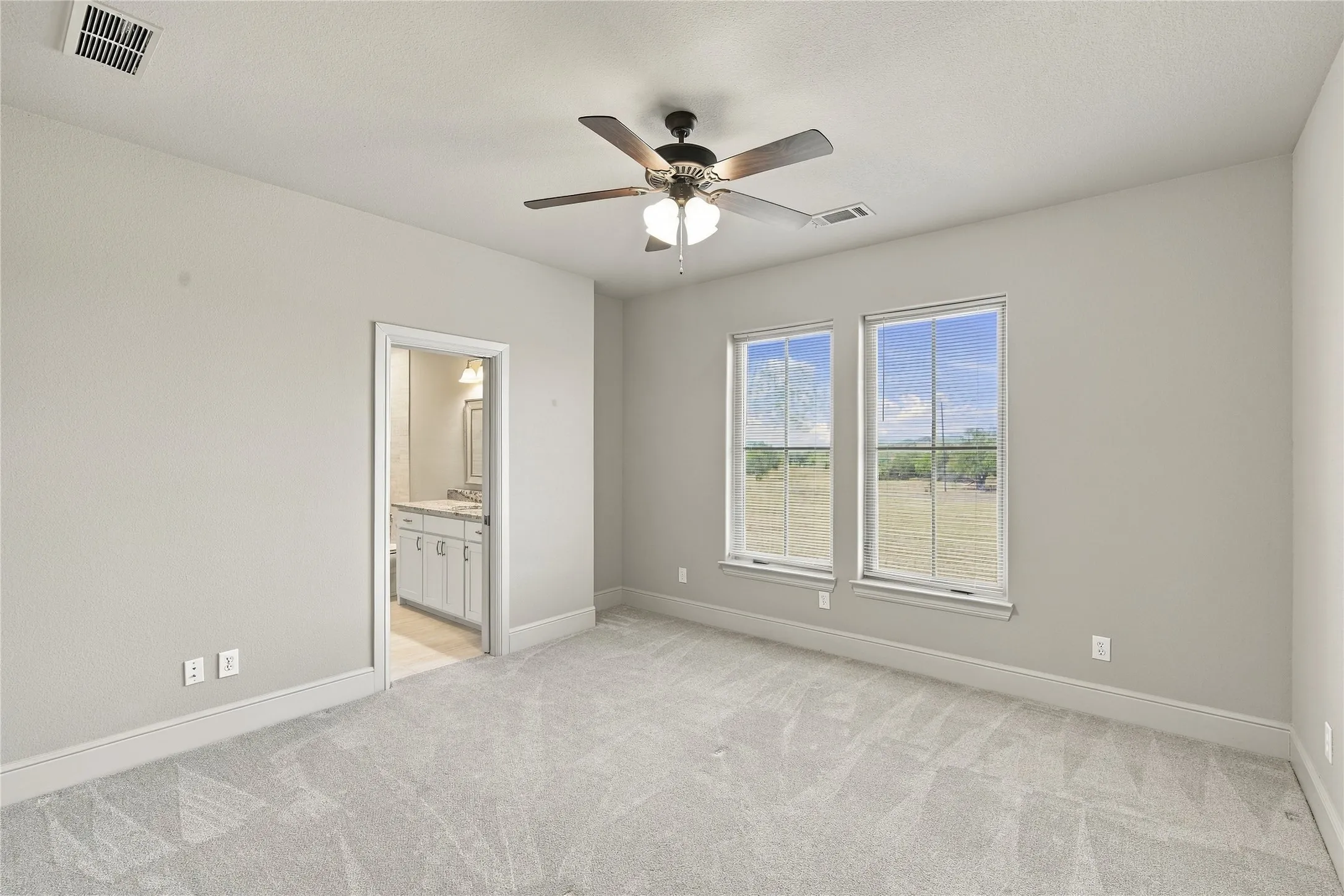 Plush carpet and two large windows make this bedroom a cozy retreat for guests or family.