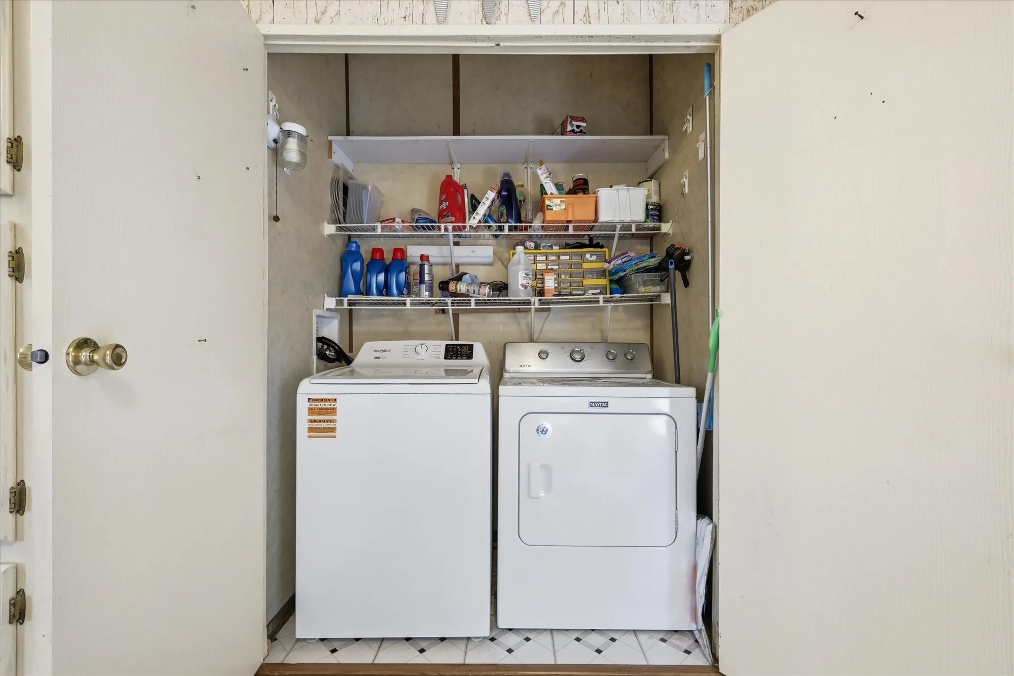 Recessed laundry area featuring a washer and dryer, wire shelving, and tiled flooring