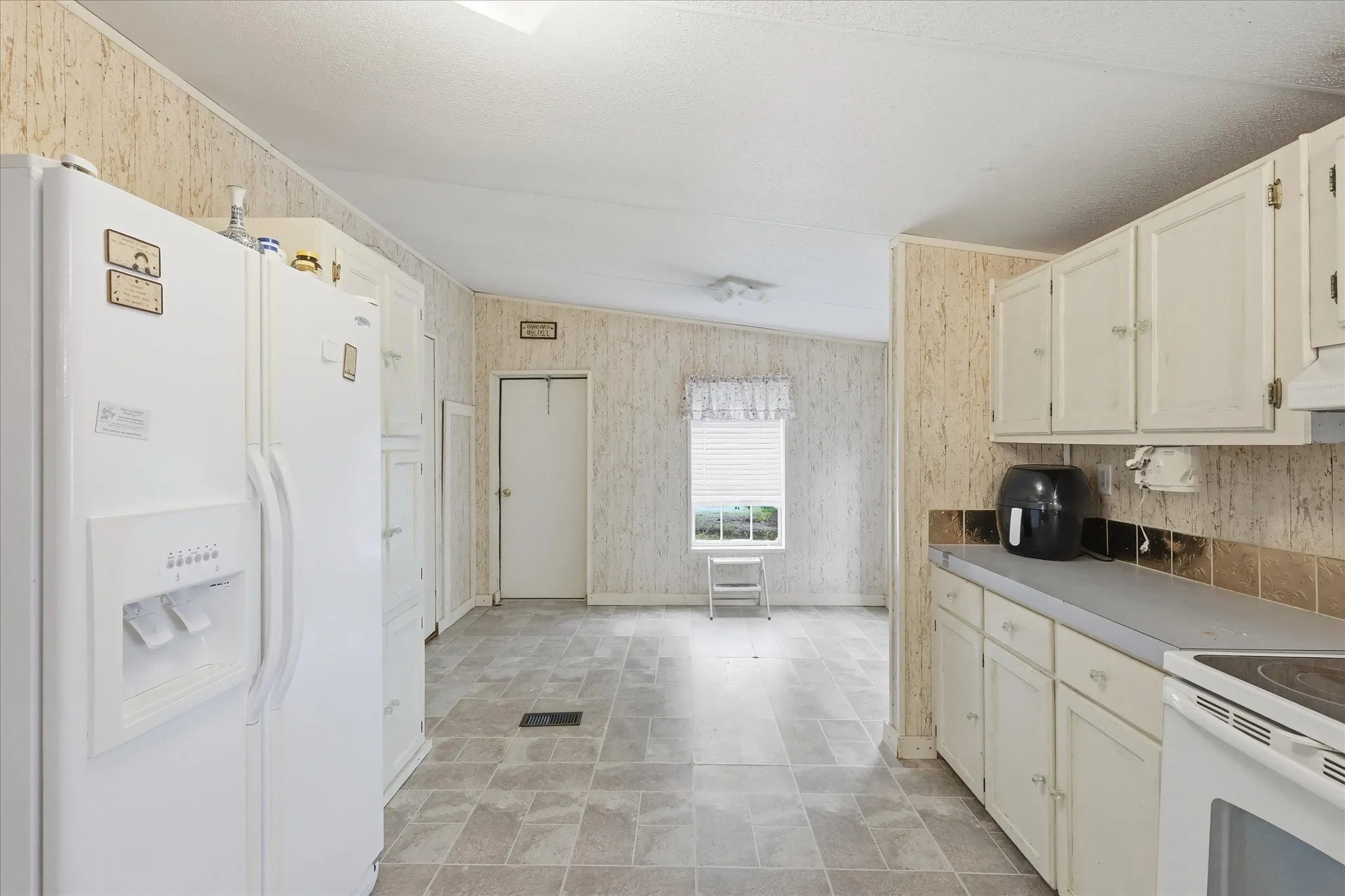 Kitchen featuring a refrigerator, white cabinetry, light-toned countertops, and tile flooring