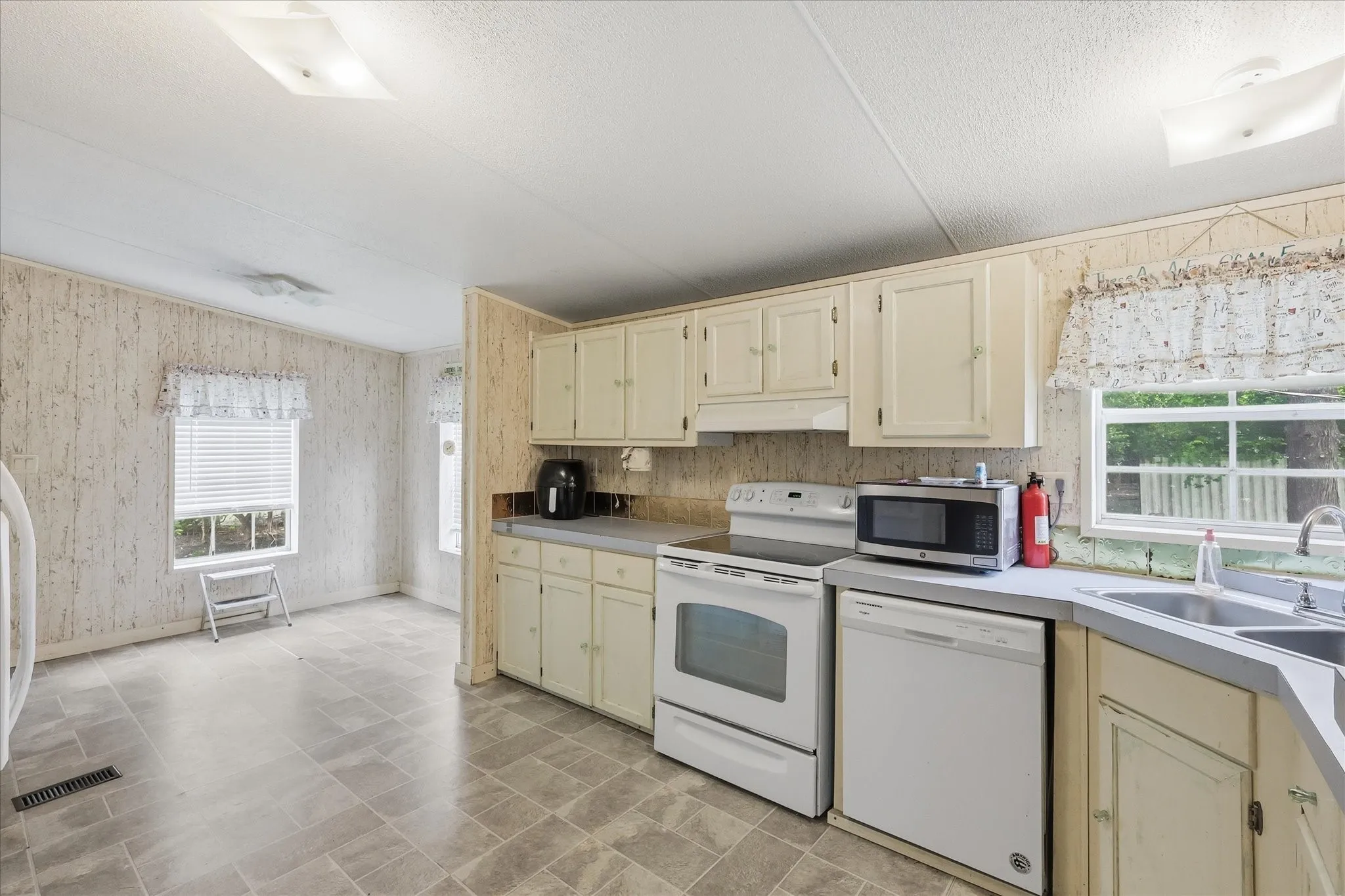 Functional kitchen featuring a double basin sink, white range, and dishwasher