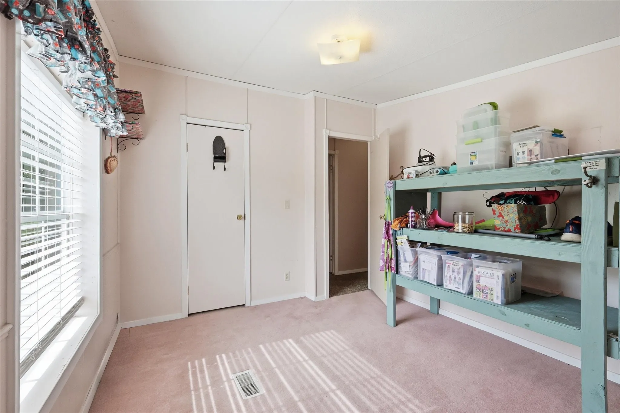 Window with blinds, wall-to-wall carpeting, white interior door, ceiling-mounted light fixture, and paneling on walls
