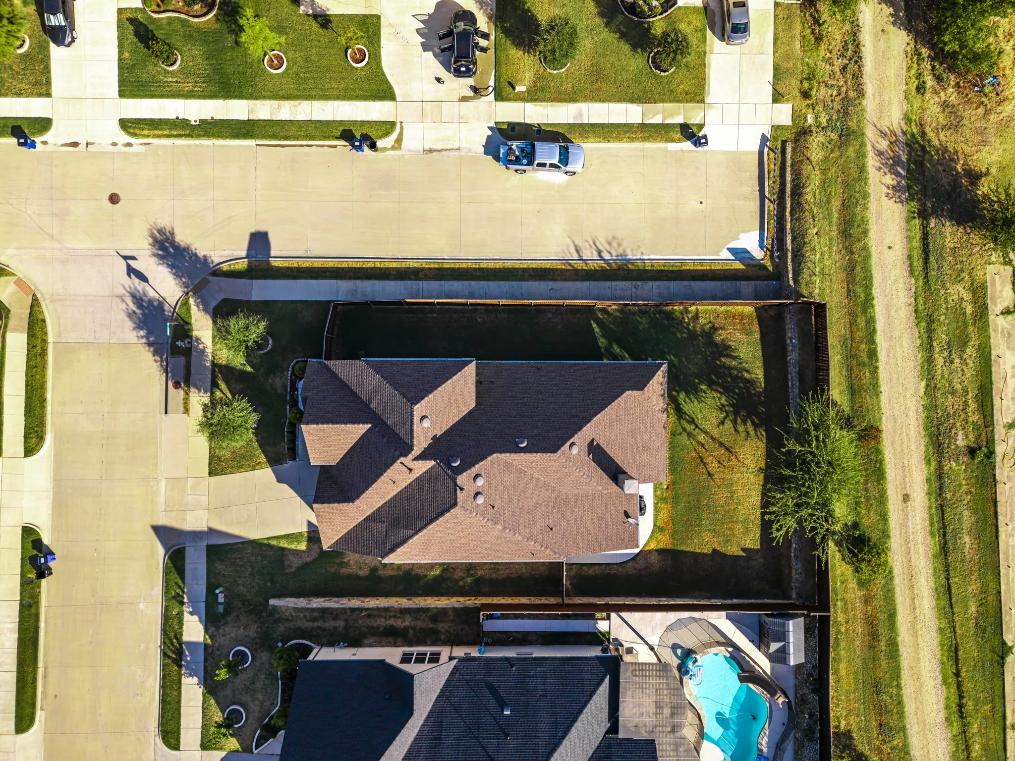 Residential property featuring a shingle roof and a spacious backyard with established trees