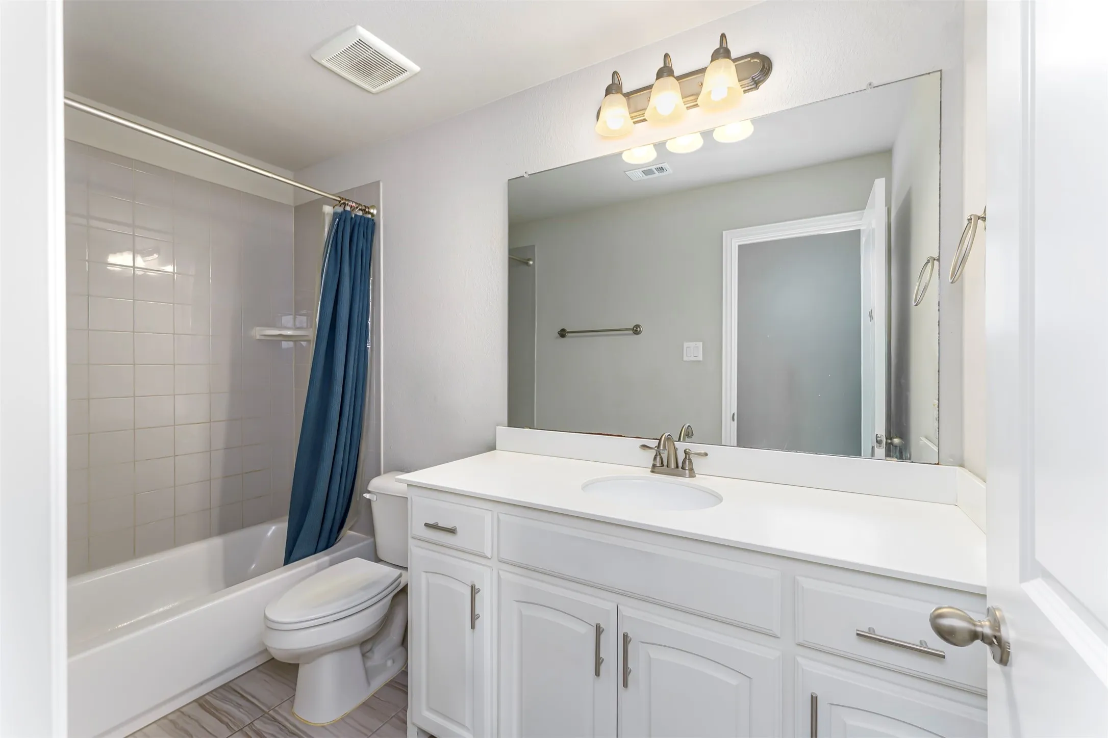 White vanity with shaker-style cabinetry, a single basin sink, and a large mirror