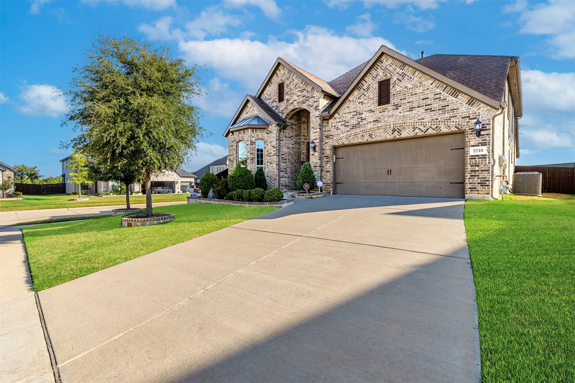Brick exterior with stone accents, an arched entryway, an attached two-car garage, and a concrete driveway