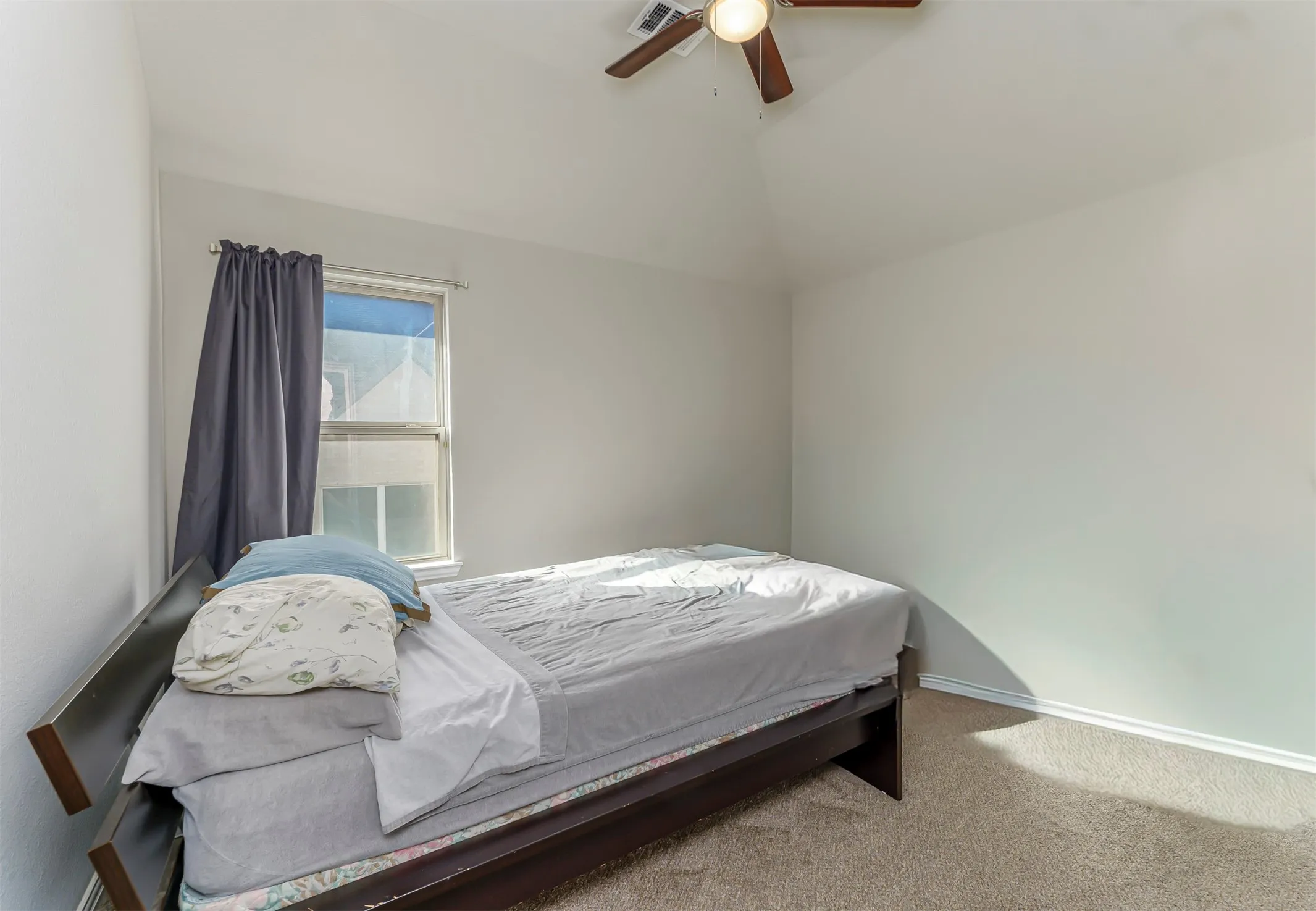 Vaulted ceiling with a ceiling fan, window with curtain rod, and carpeted flooring