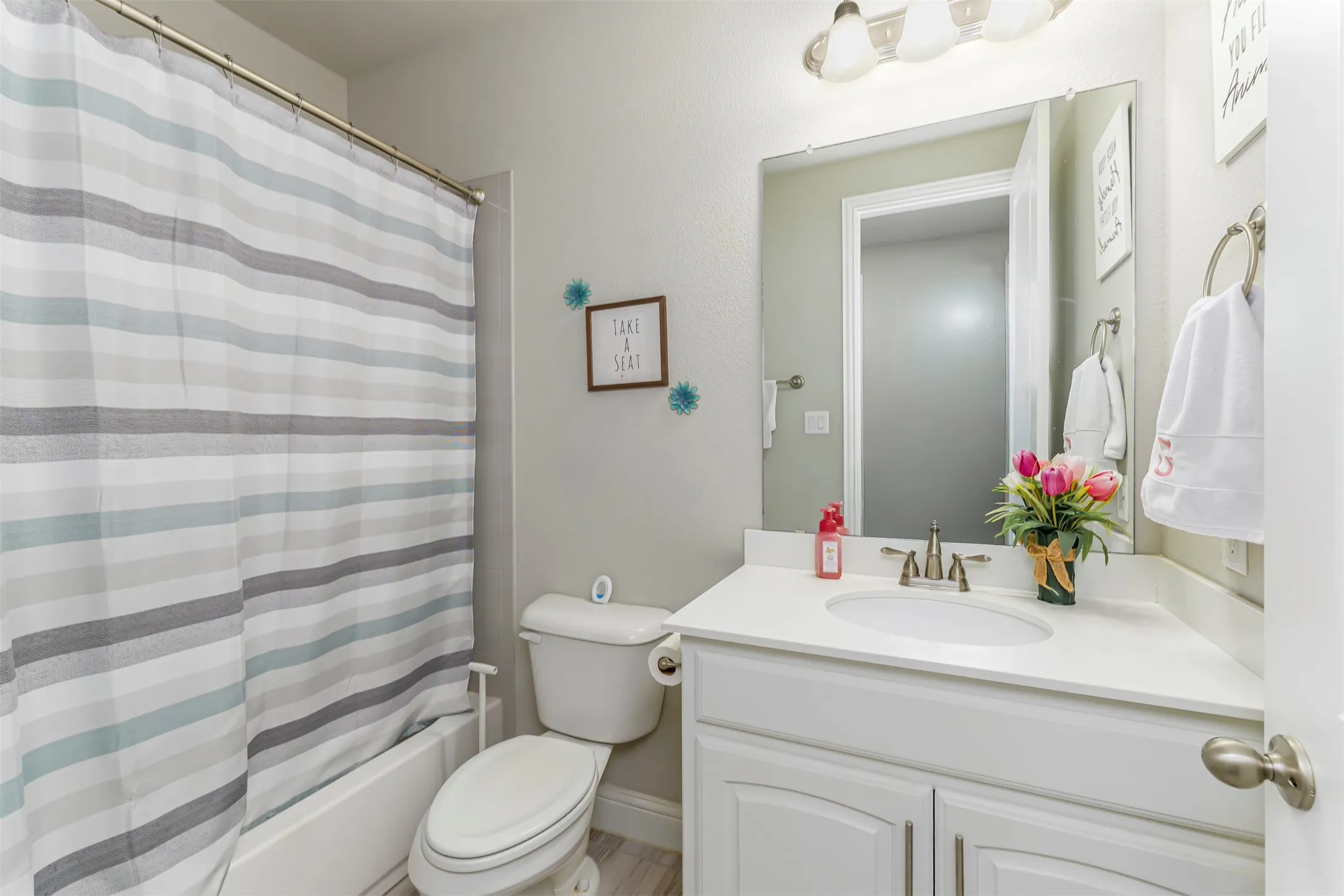 White vanity with integrated sink, brushed nickel faucet, and a wall-mounted mirror