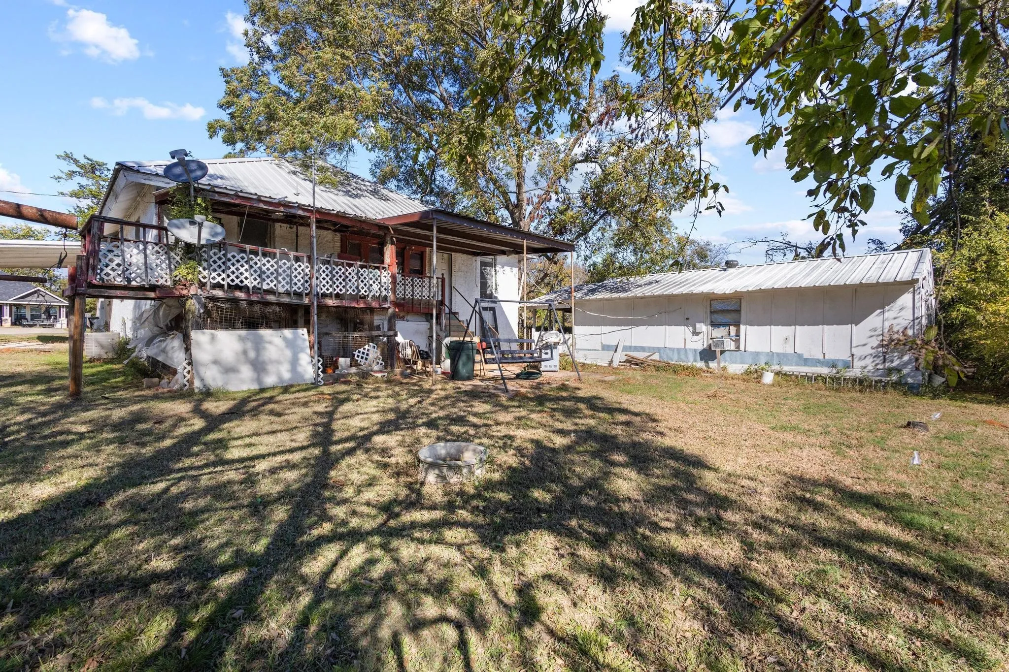 Exterior featuring a raised porch with white lattice railing and a covered metal roof