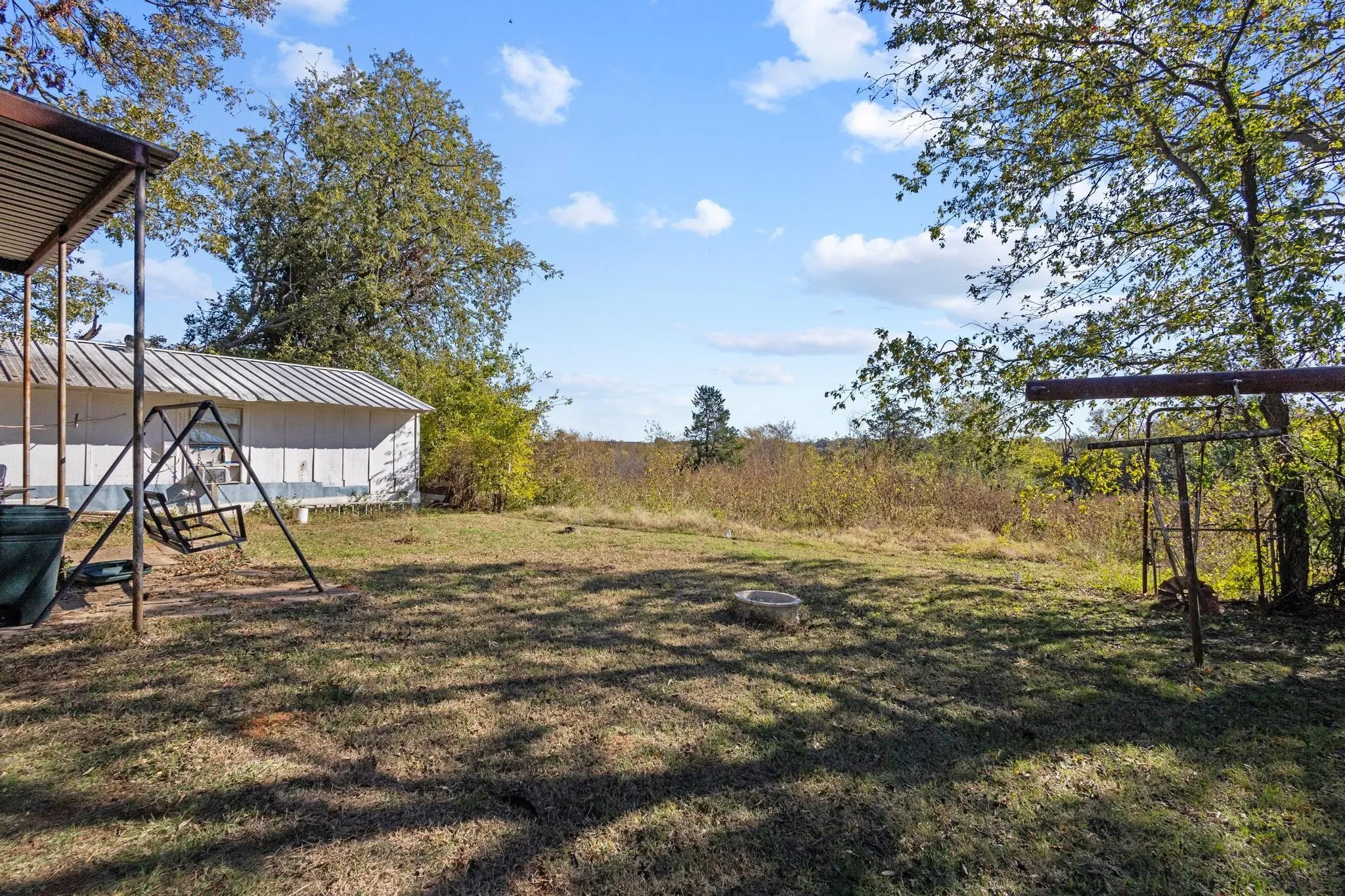 Expansive grassy yard with mature trees and a metal outbuilding