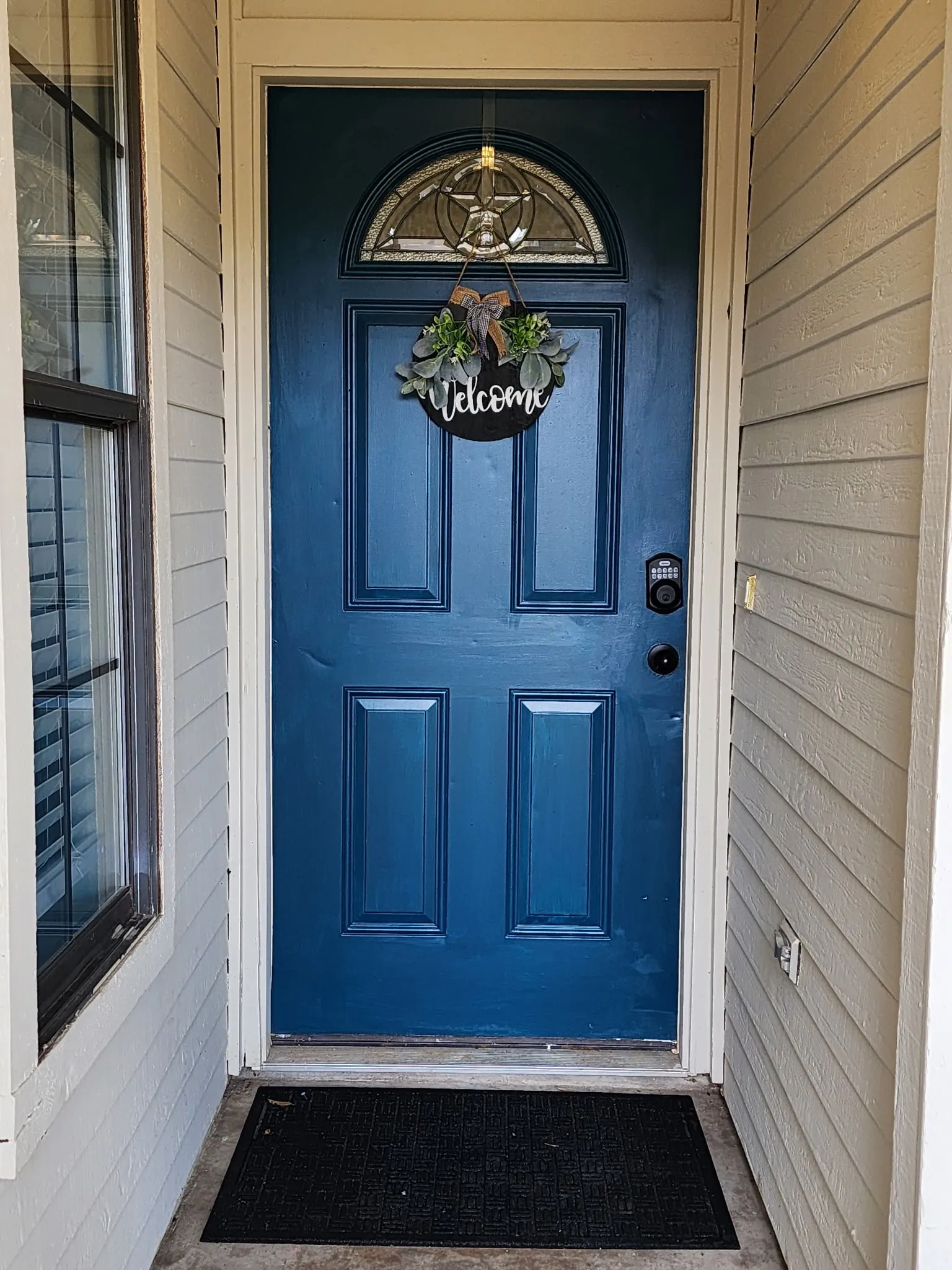 Panel front door with an arched stained-glass transom window and keyless entry