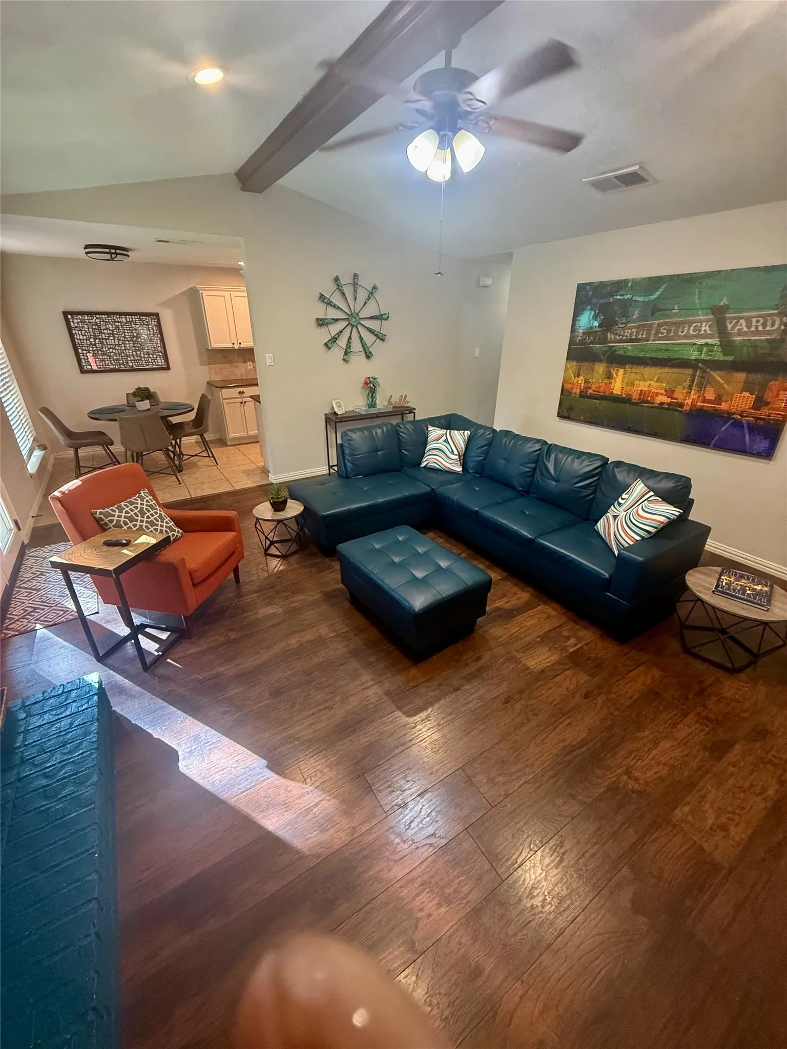 Vaulted ceiling with exposed wood-finish beam, wood-finish flooring, and recessed lighting