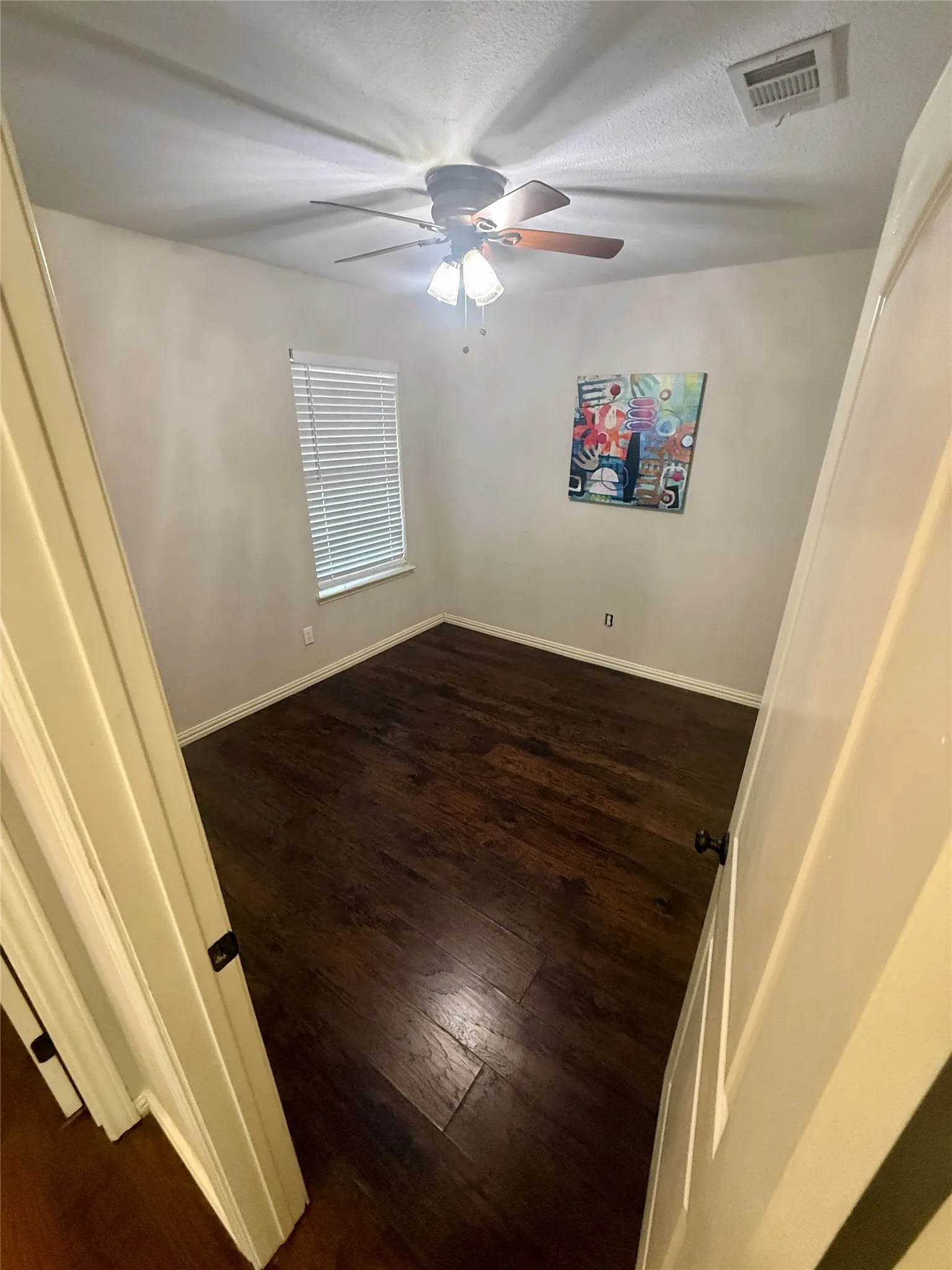 Dark wood-finish flooring with white baseboards
