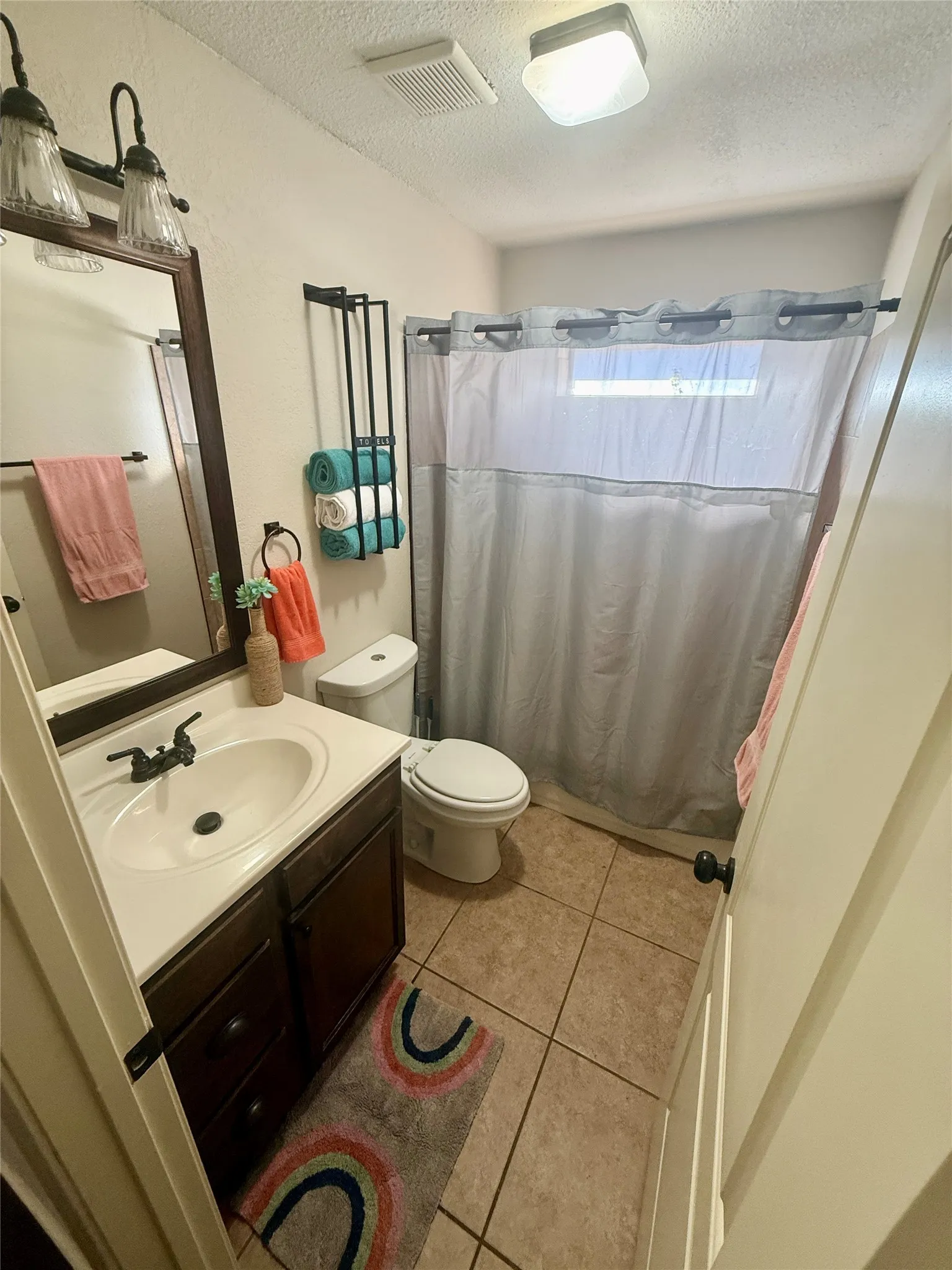 Bathroom featuring a single vanity, tile flooring, and a shower with a curtain rod