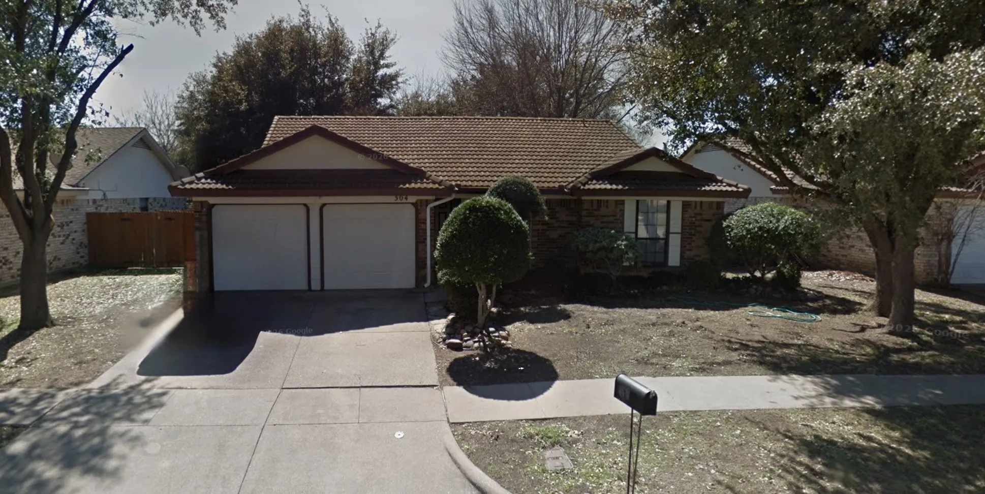 Traditional exterior with a two-car garage, concrete driveway, and mature front yard landscaping