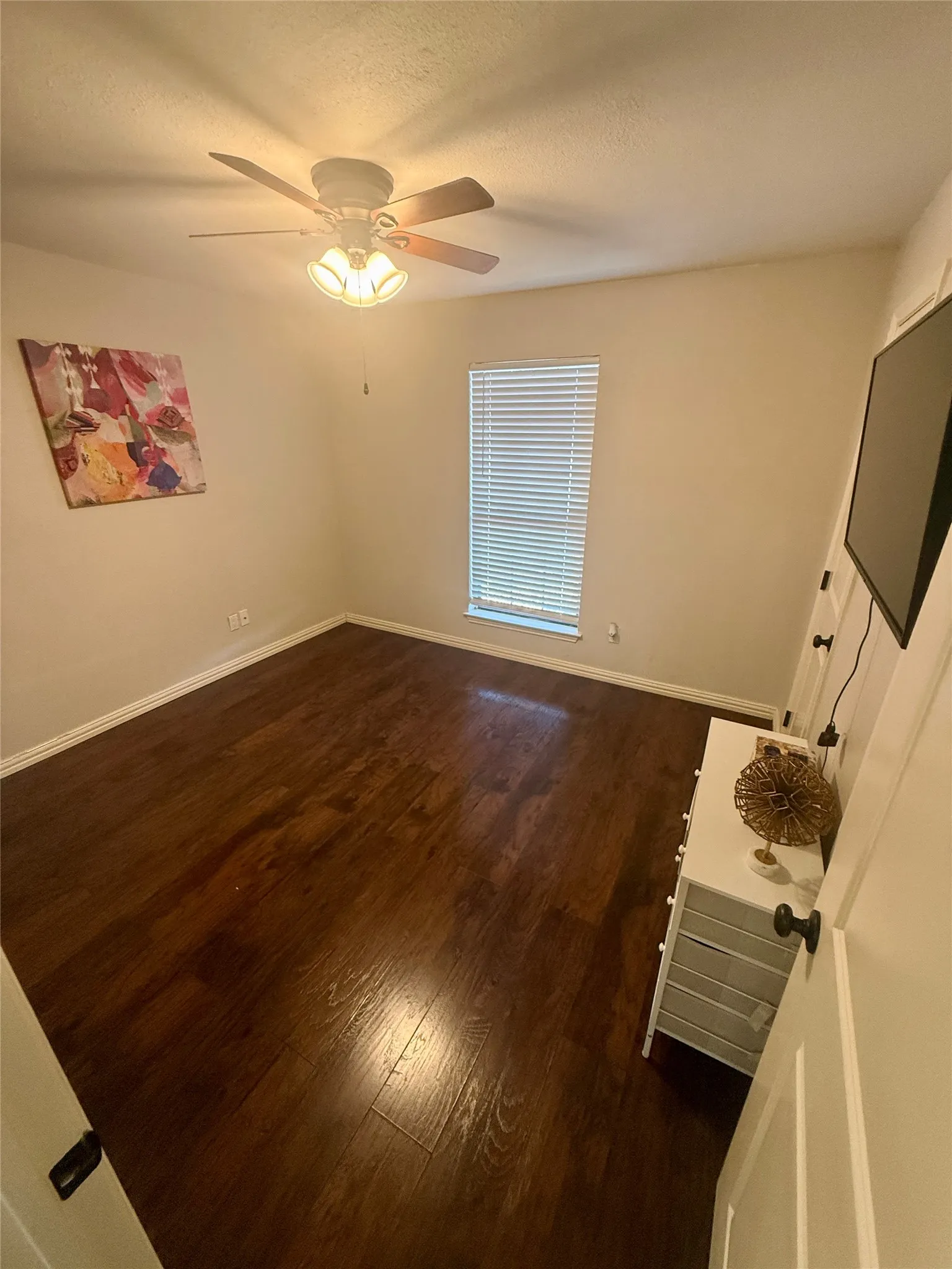 Wood-finish flooring throughout, ceiling fan with integrated lighting, and window with blinds