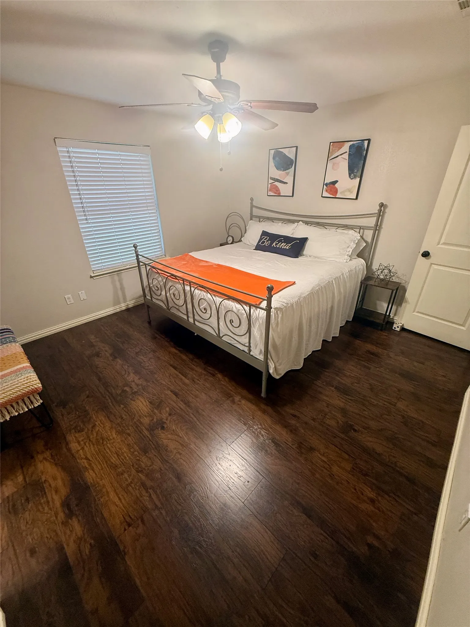 Dark wood-finish flooring, ceiling fan with integrated lighting, window with blinds, and painted walls