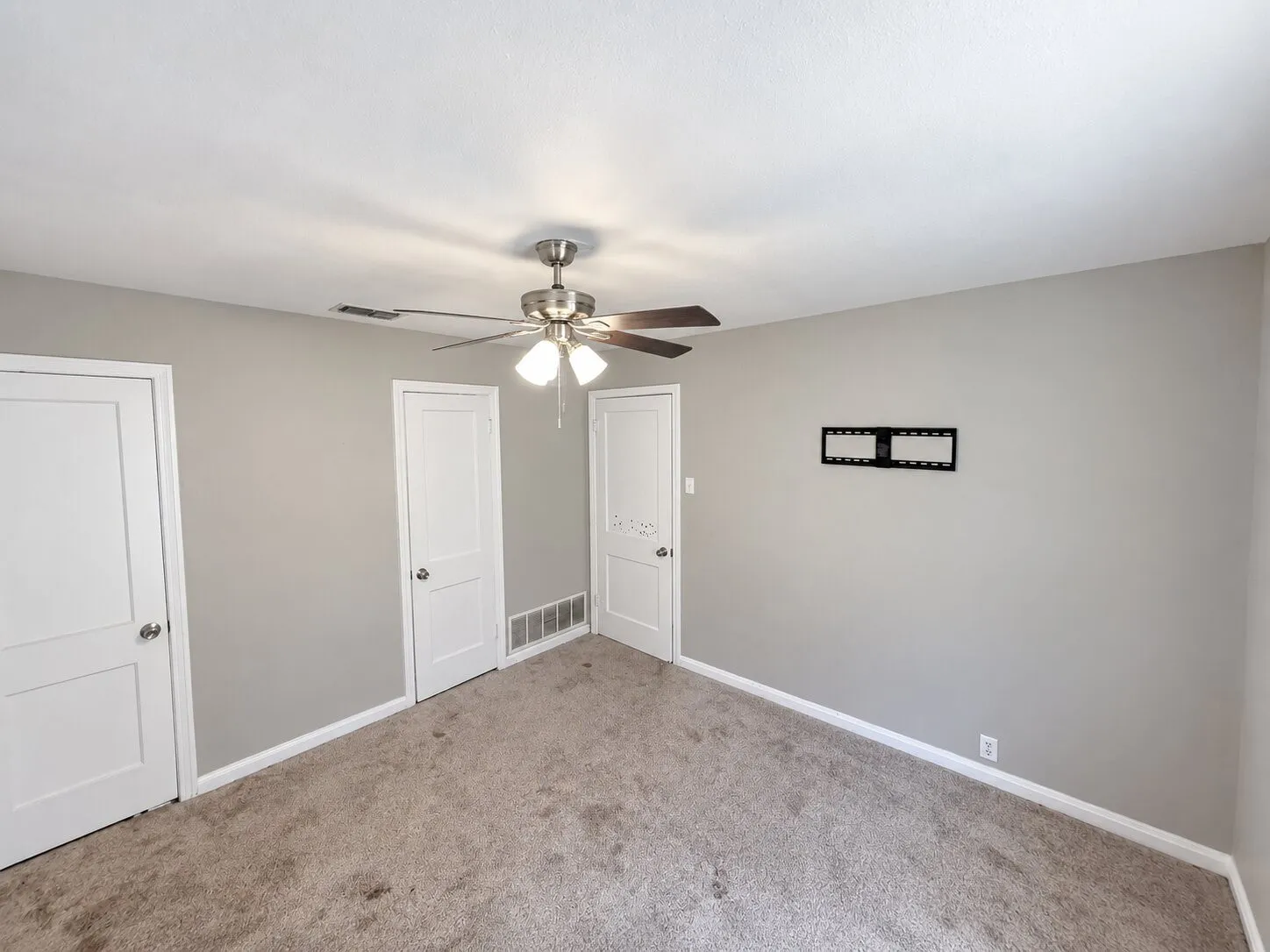 Ceiling fan with light fixture, neutral wall color, and carpet flooring