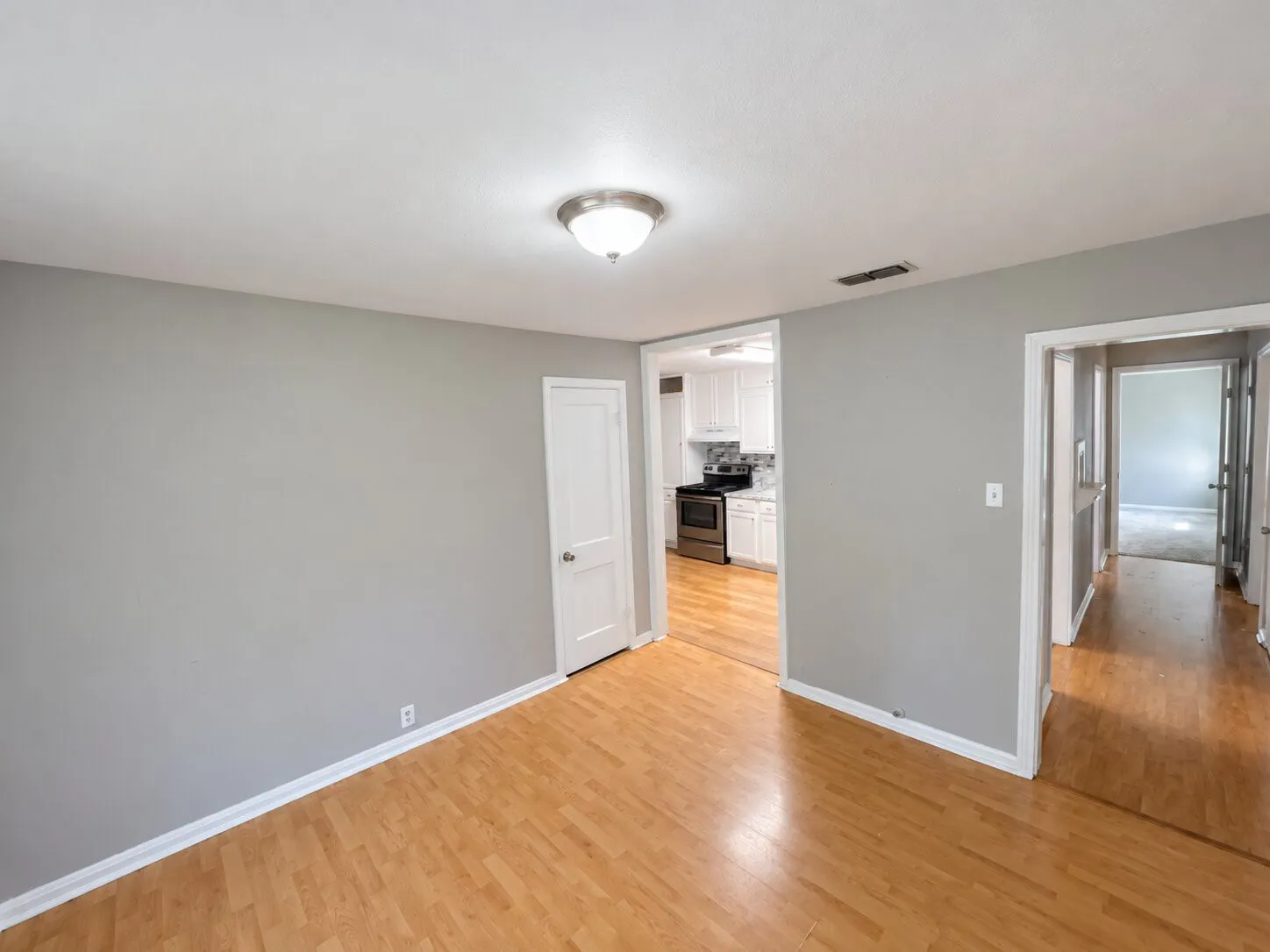 Wood-finish flooring, recessed lighting, and a white interior door