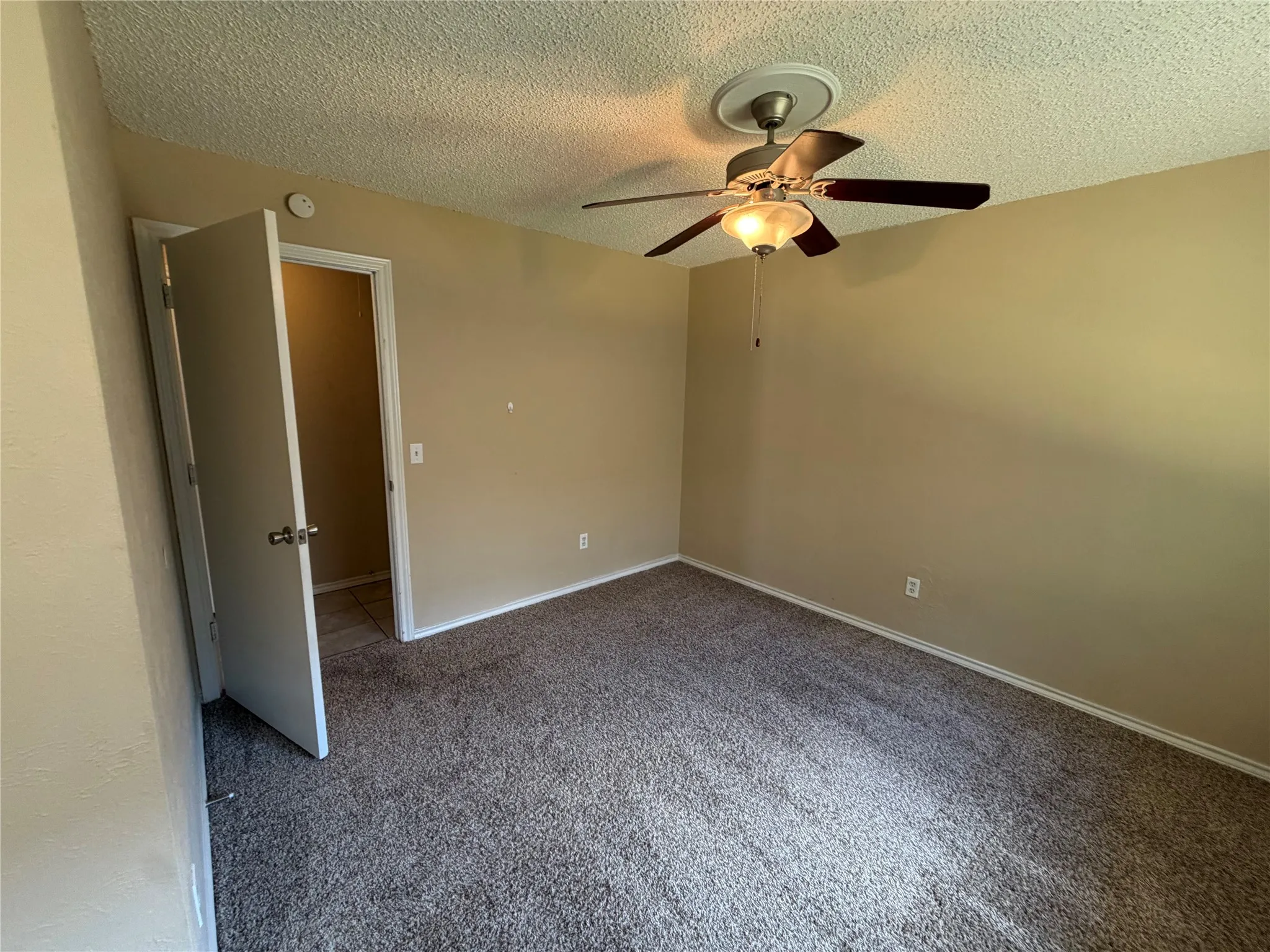 Carpeted flooring, neutral wall paint, and a ceiling fan with integrated lighting