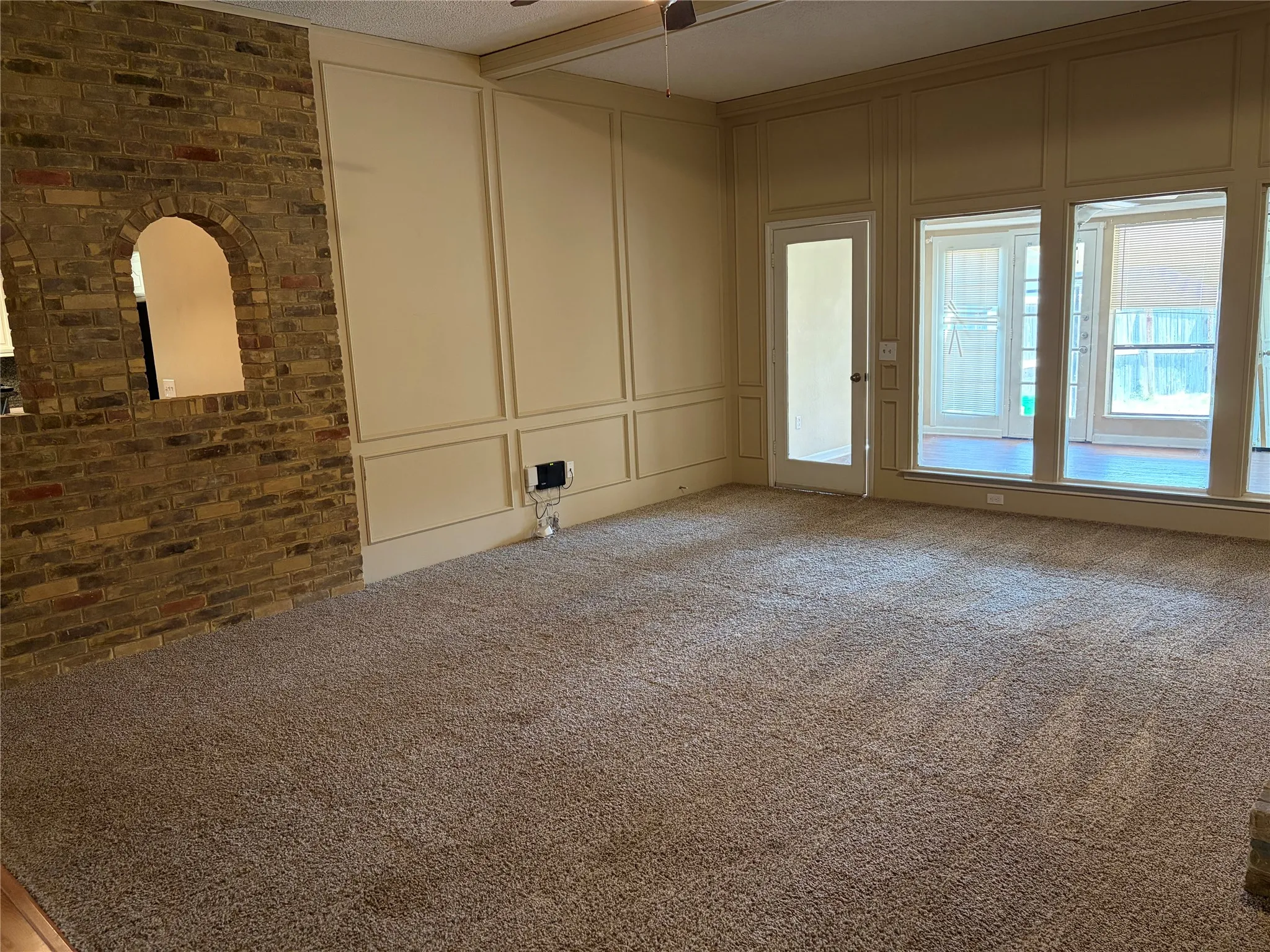 Brick accent wall with arched pass-through, paneled walls, and plush carpeting