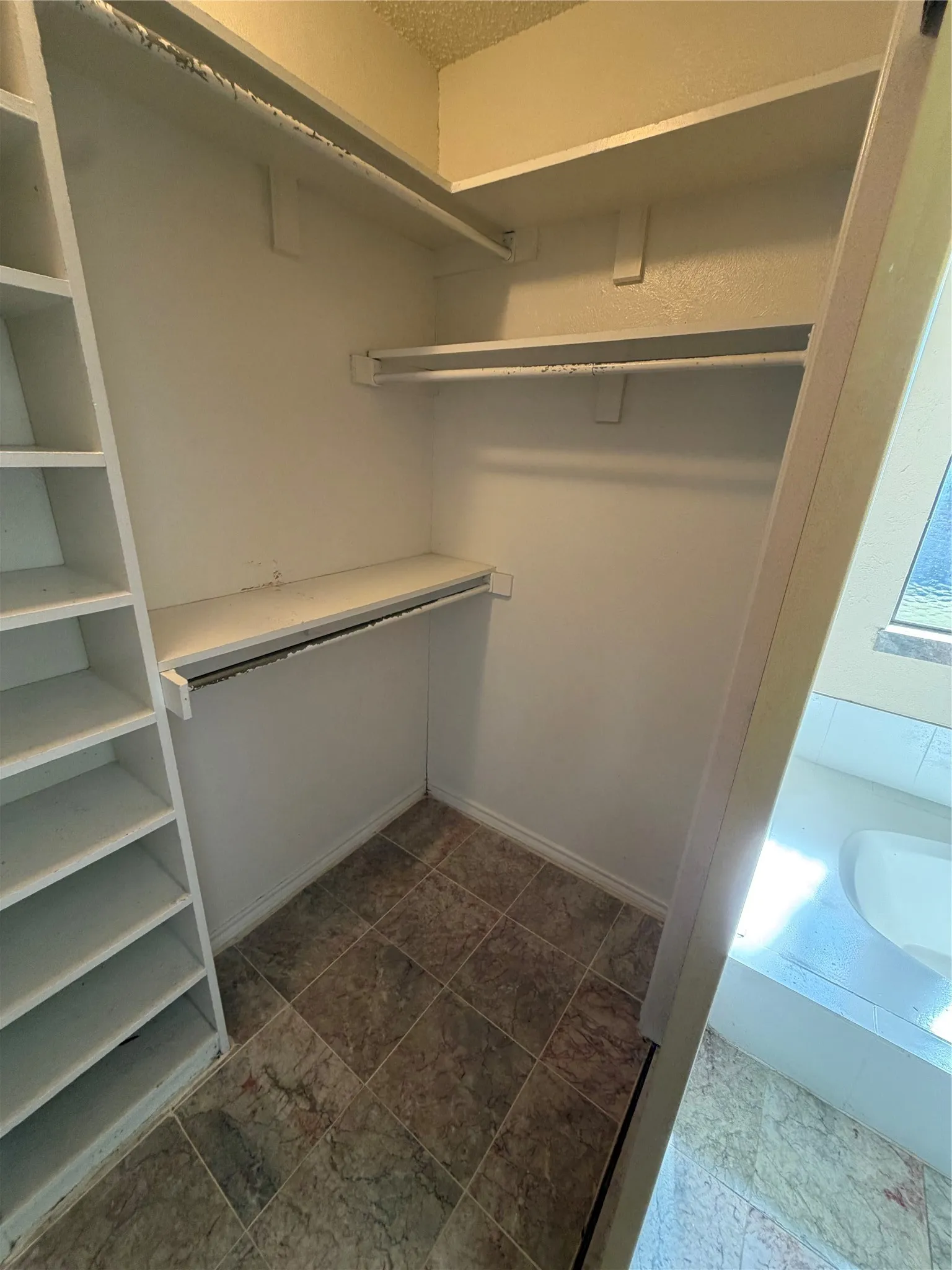Built-in shelving, multiple hanging rods, and a tiled floor