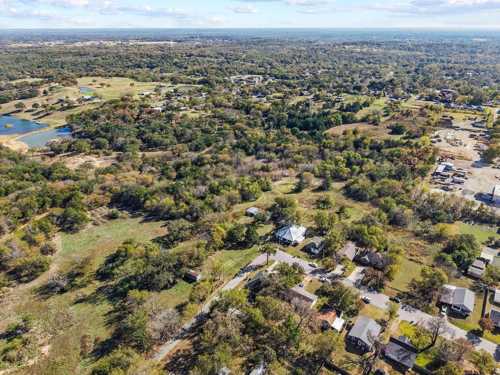 Expansive rural landscape featuring scattered residential properties, mature trees, and a visible pond