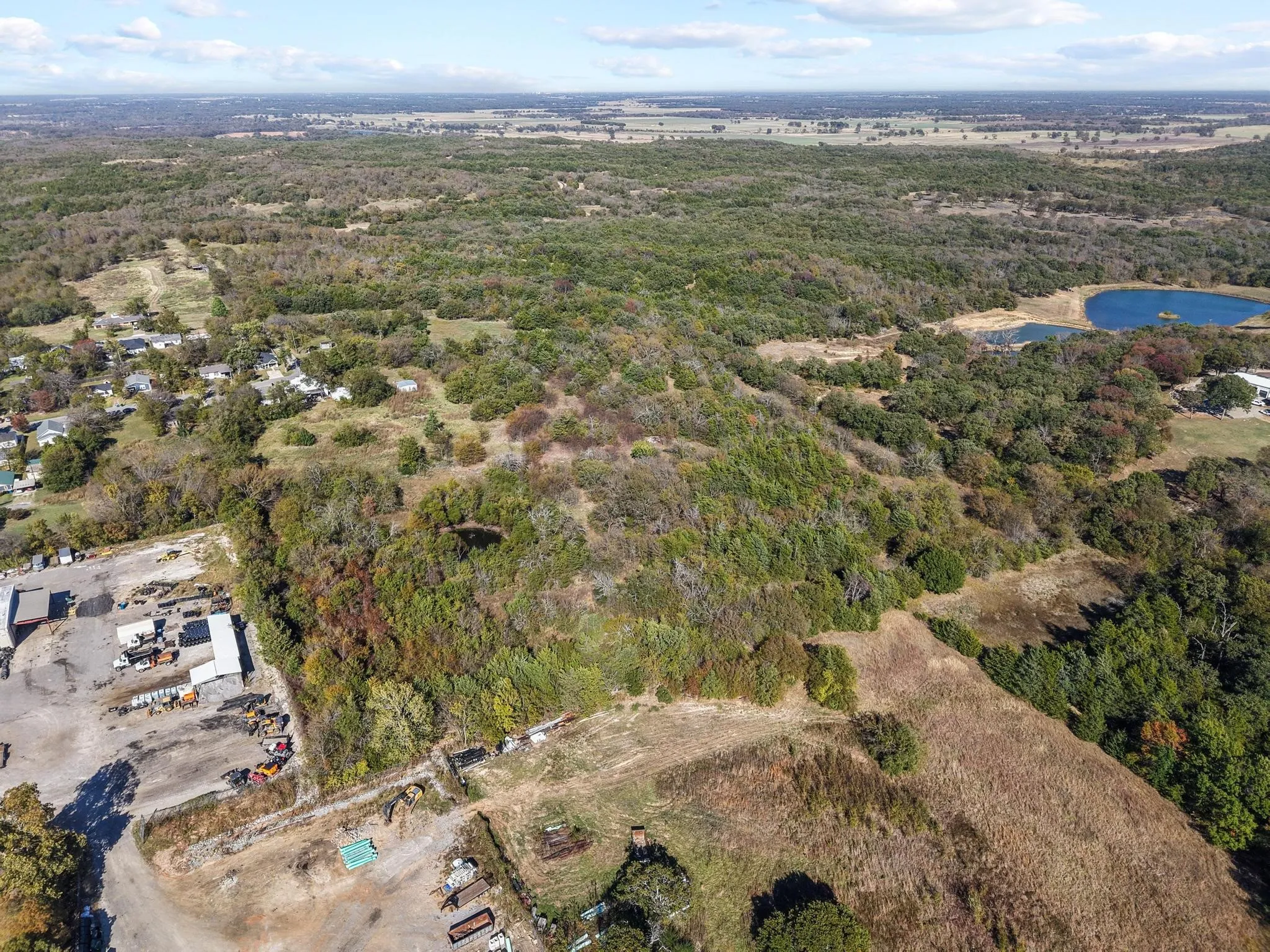 Expansive land parcel featuring varied topography, mature trees, and a natural pond