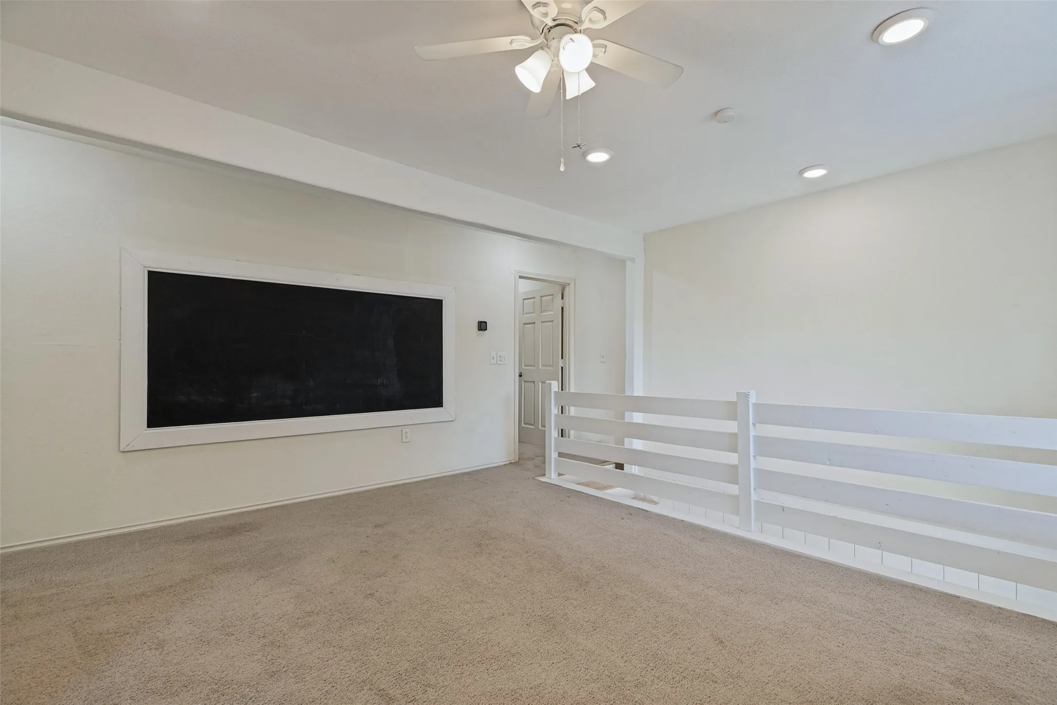 Recessed lighting, ceiling fan, built-in chalkboard, interior railing, and neutral carpeting