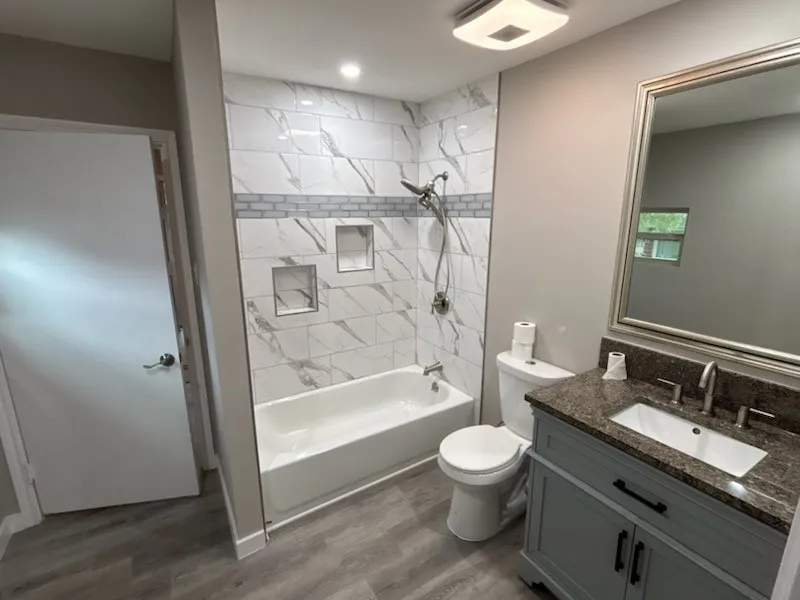 Bathtub with tile surround featuring an accent band and built-in niches