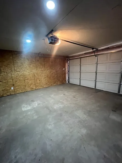 Attached garage with a concrete floor, panel garage door, and overhead lighting