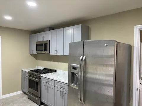 Kitchen featuring light grey cabinetry, stainless steel appliances, light-toned countertops, and recessed lighting