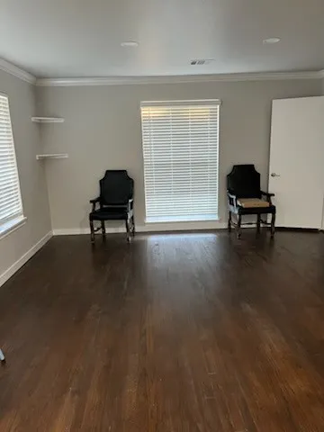 Dark wood-finish flooring, crown molding, recessed lighting, and dual windows with blinds