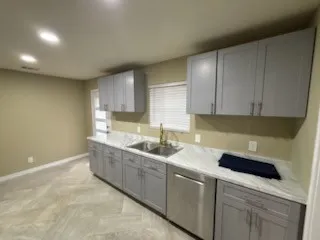 Modern kitchen featuring grey shaker-style cabinetry, a stainless steel double basin sink, and a stainless steel dishwasher