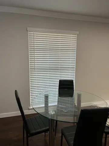 Crown molding details a neutral wall with window featuring horizontal blinds