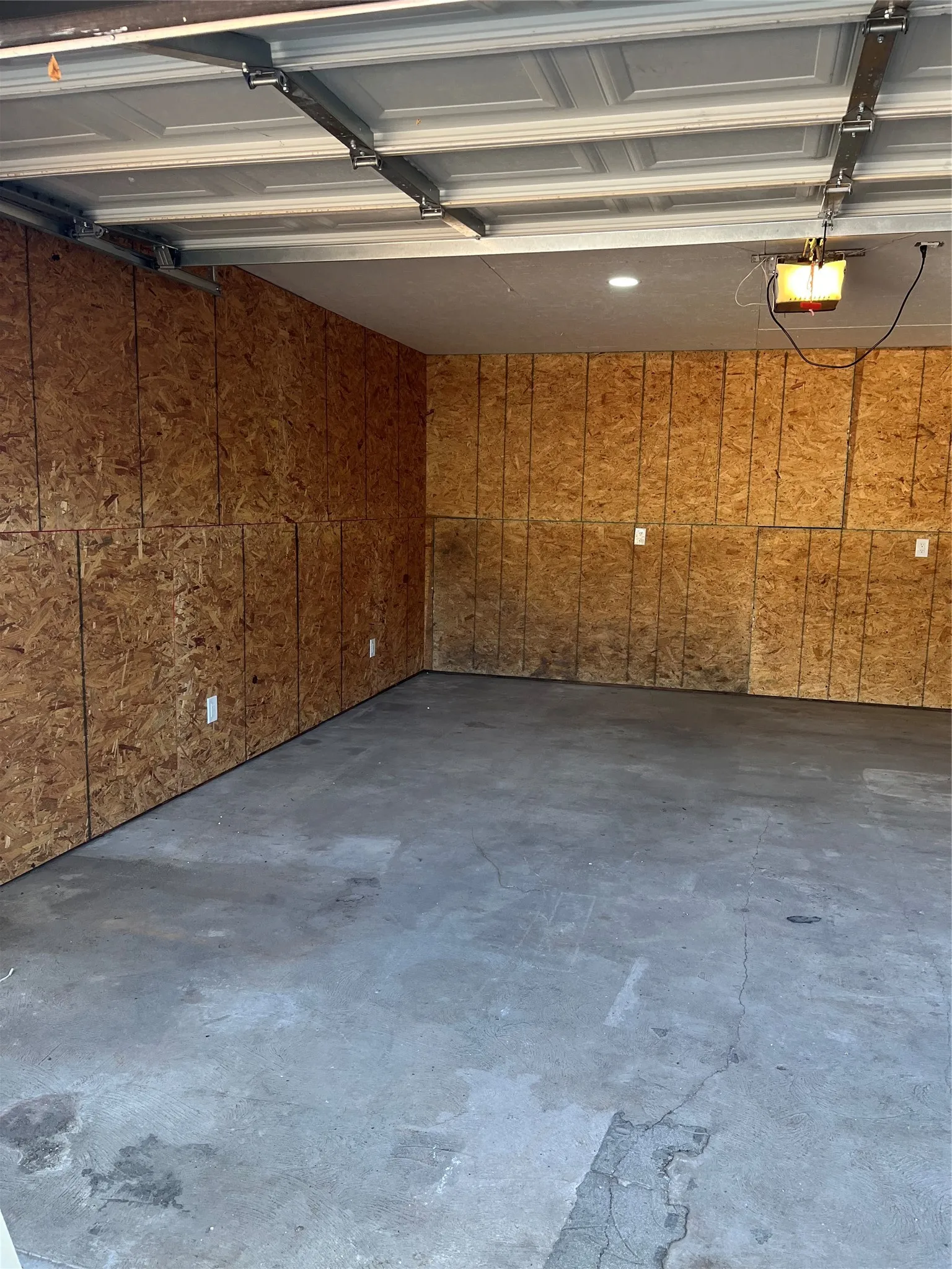 Concrete flooring with oriented strand board walls and a paneled garage door