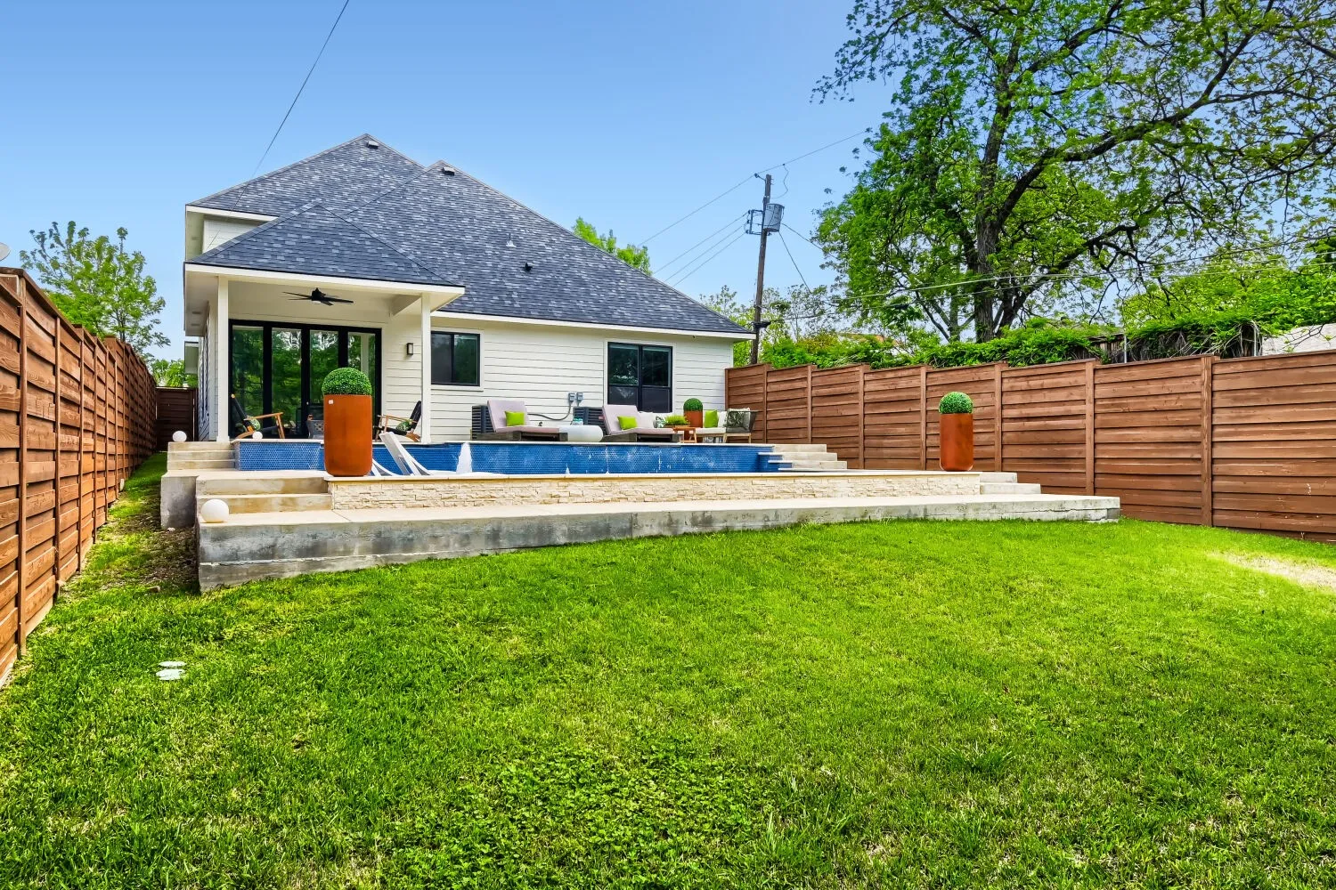 Rear view of house featuring a patio area, ceiling fan, a shingled roof, and a fenced backyard