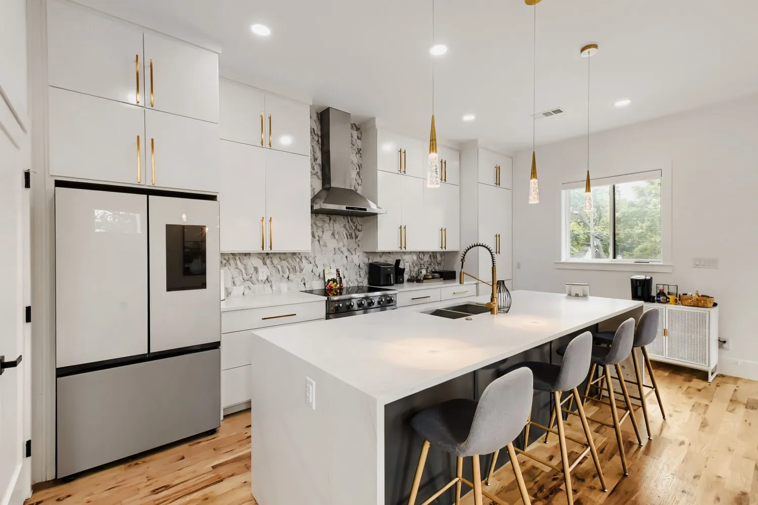 Kitchen featuring smart refrigerator, white cabinetry, a breakfast bar area, a kitchen island with sink, and pendant lighting