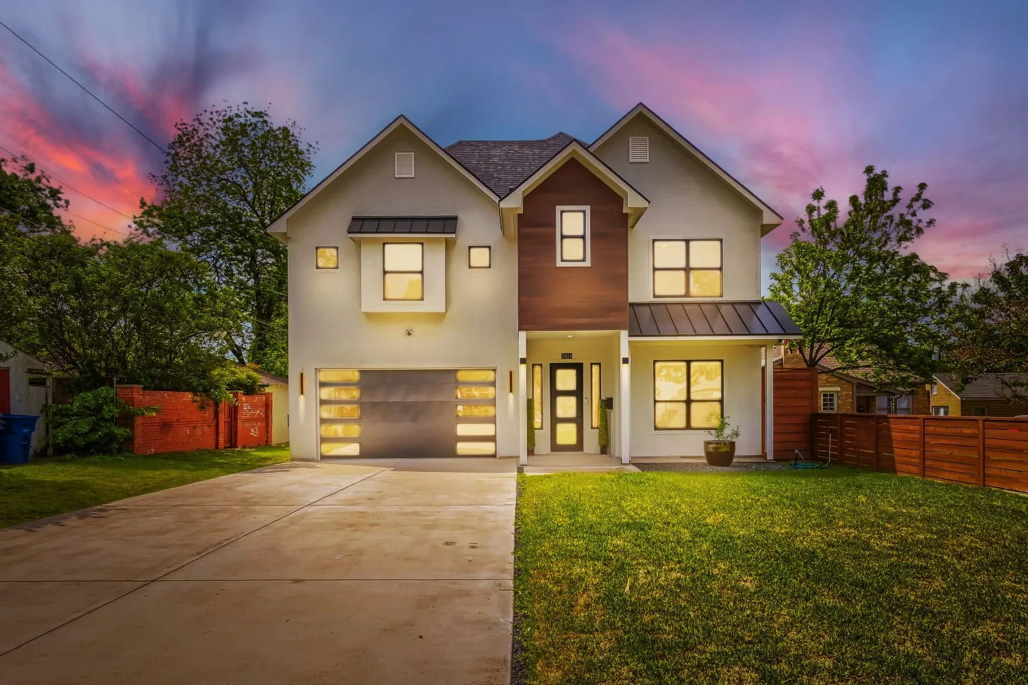 View of front of house featuring a standing seam roof, a garage, driveway, and stucco siding