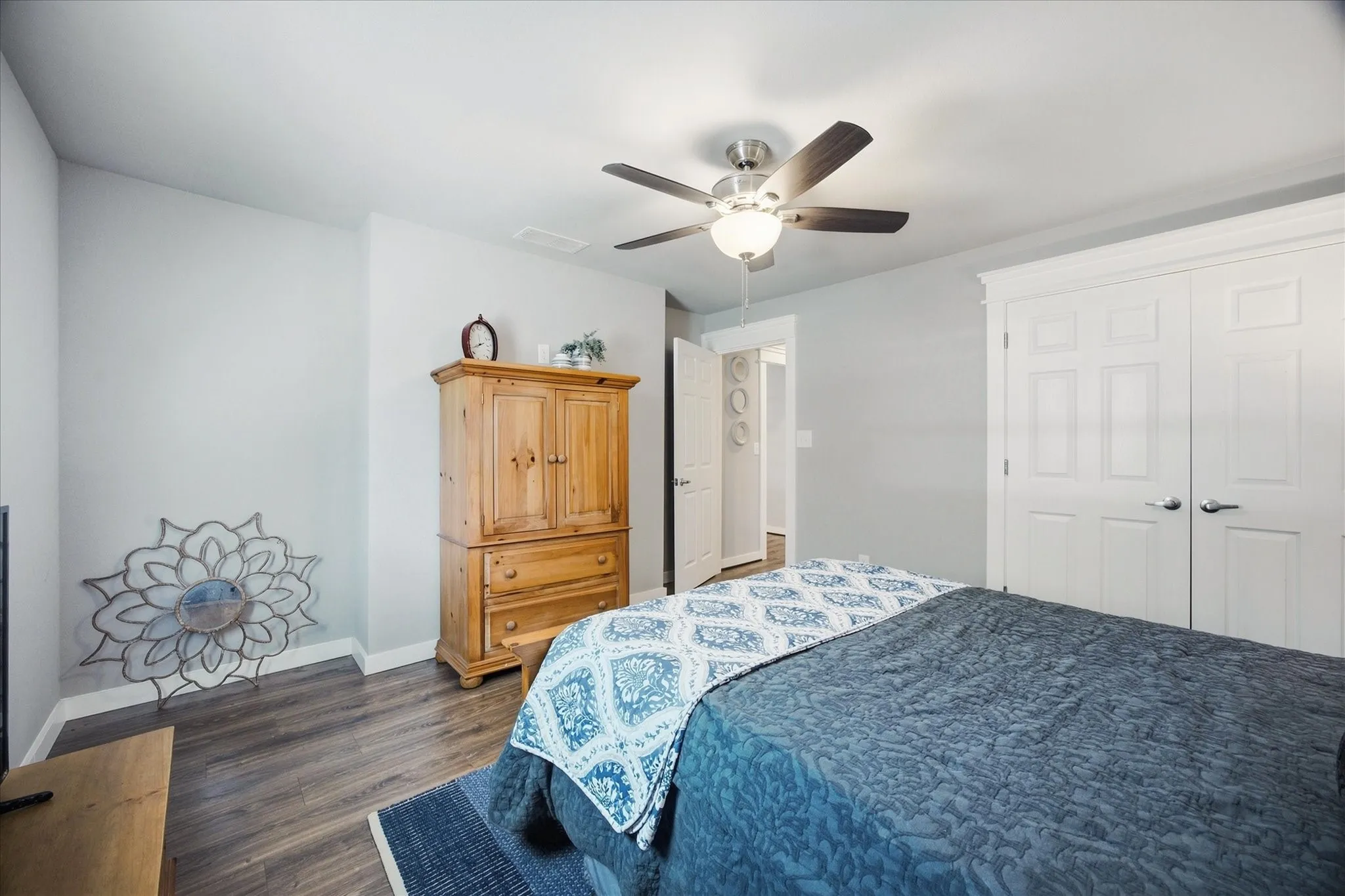 Wood-finish flooring, white paneled doors with brushed nickel hardware, and a ceiling fan with light fixture