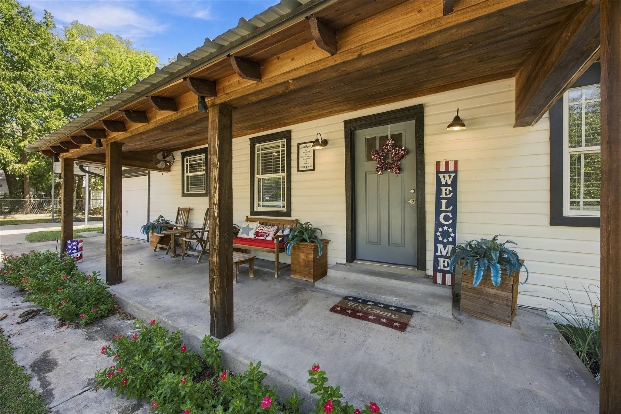 Covered front porch featuring wood support beams, a wood-paneled ceiling, and exterior lighting