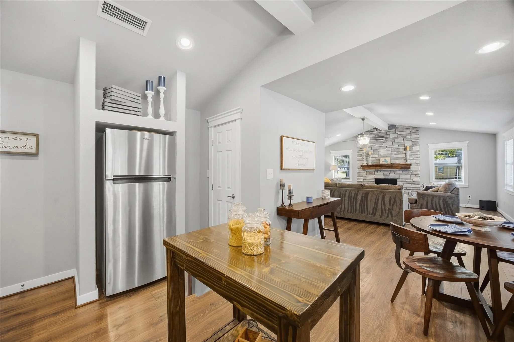 Vaulted ceilings with recessed lighting, stone-clad fireplace with wood mantel, wood-finish flooring, and built-in shelving