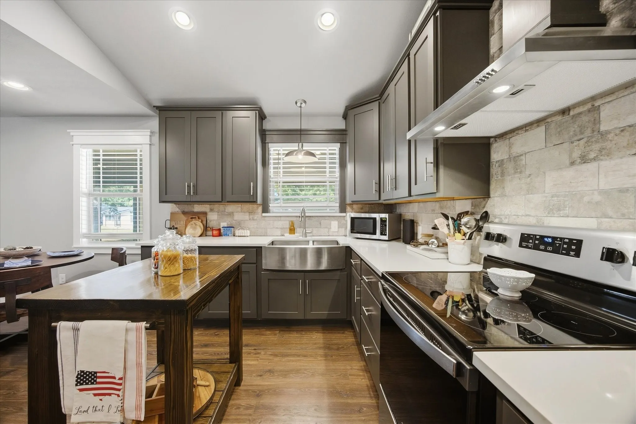 Galley kitchen featuring wood-finish flooring, recessed lighting, gray cabinetry, white countertops, and a subway tile backsplash