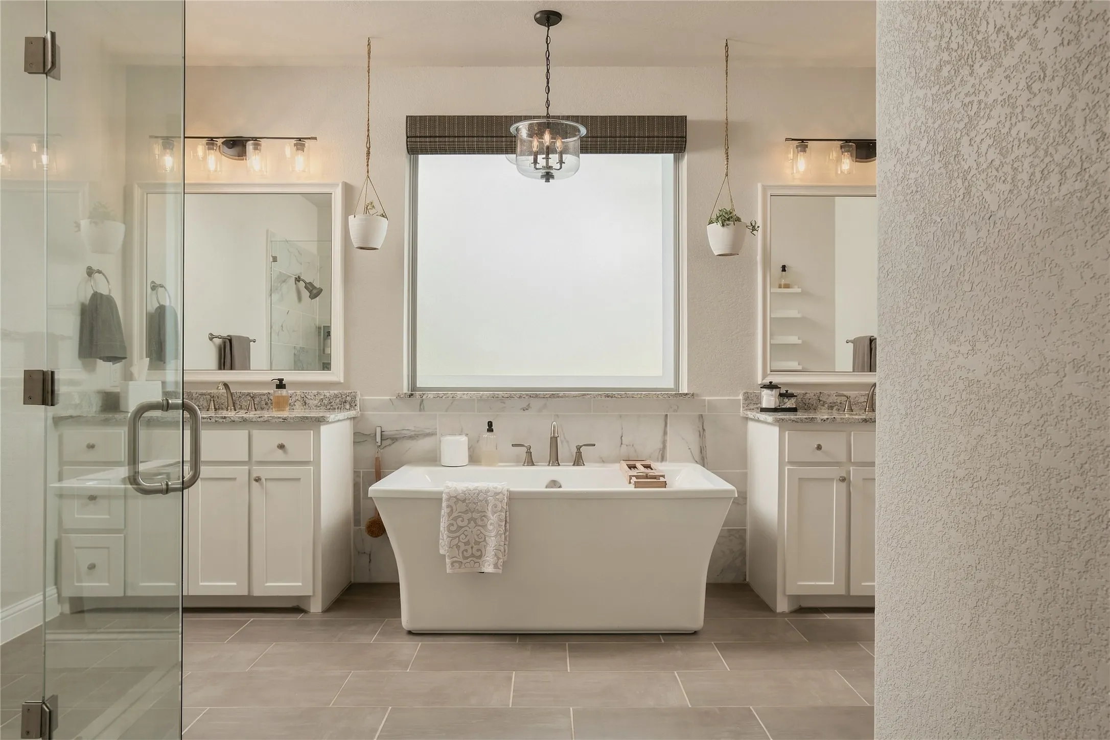 A light-filled primary bath creates a spa-like experience with a freestanding soaking tub, dual vanities and oversized glass shower.
